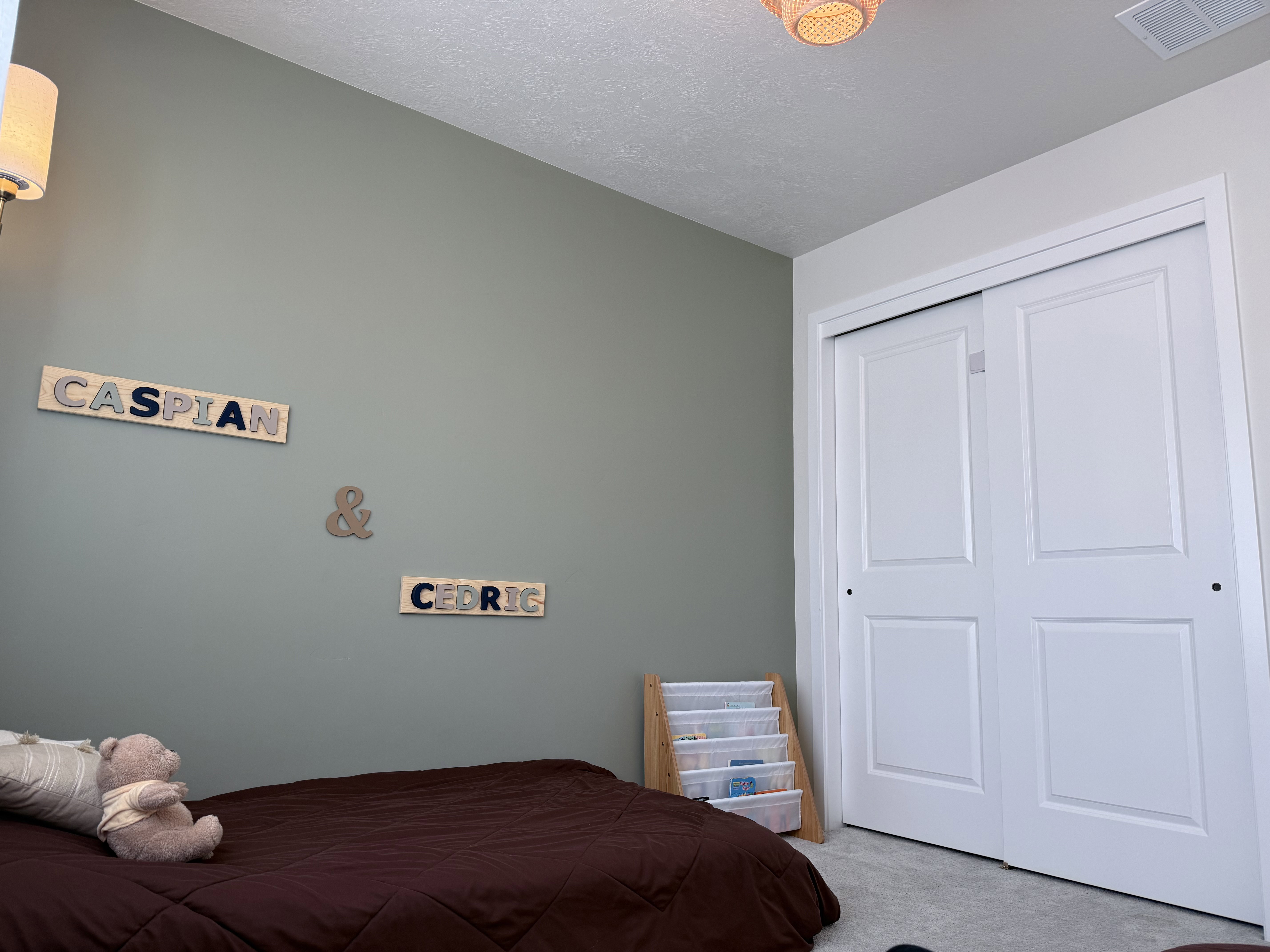 Room featuring a light green wall, white bi-fold closet doors, wall-mounted lighting fixture, and textured ceiling