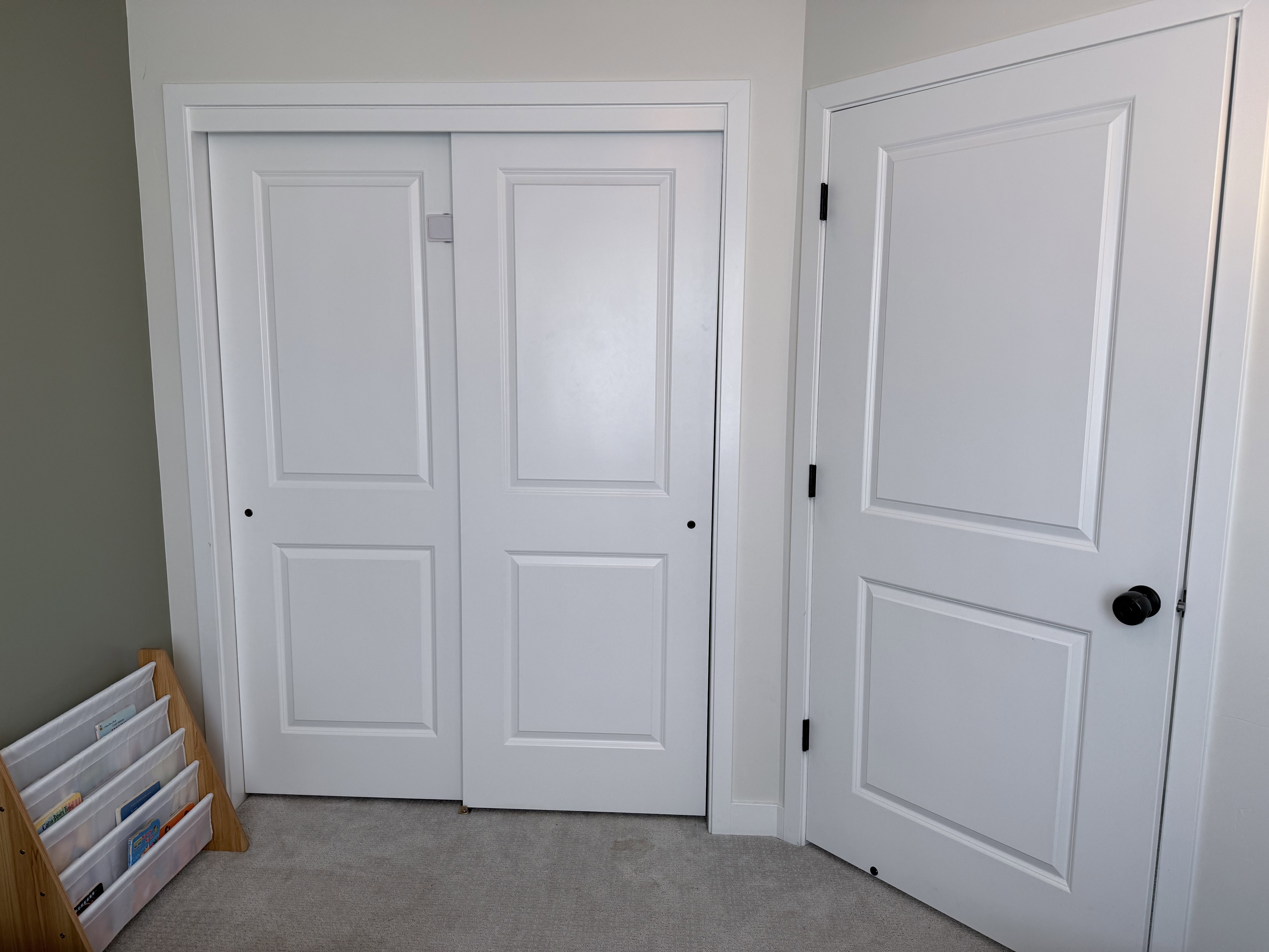 Paneled bifold closet doors with a matte black knob, complemented by an interior door with matching hardware