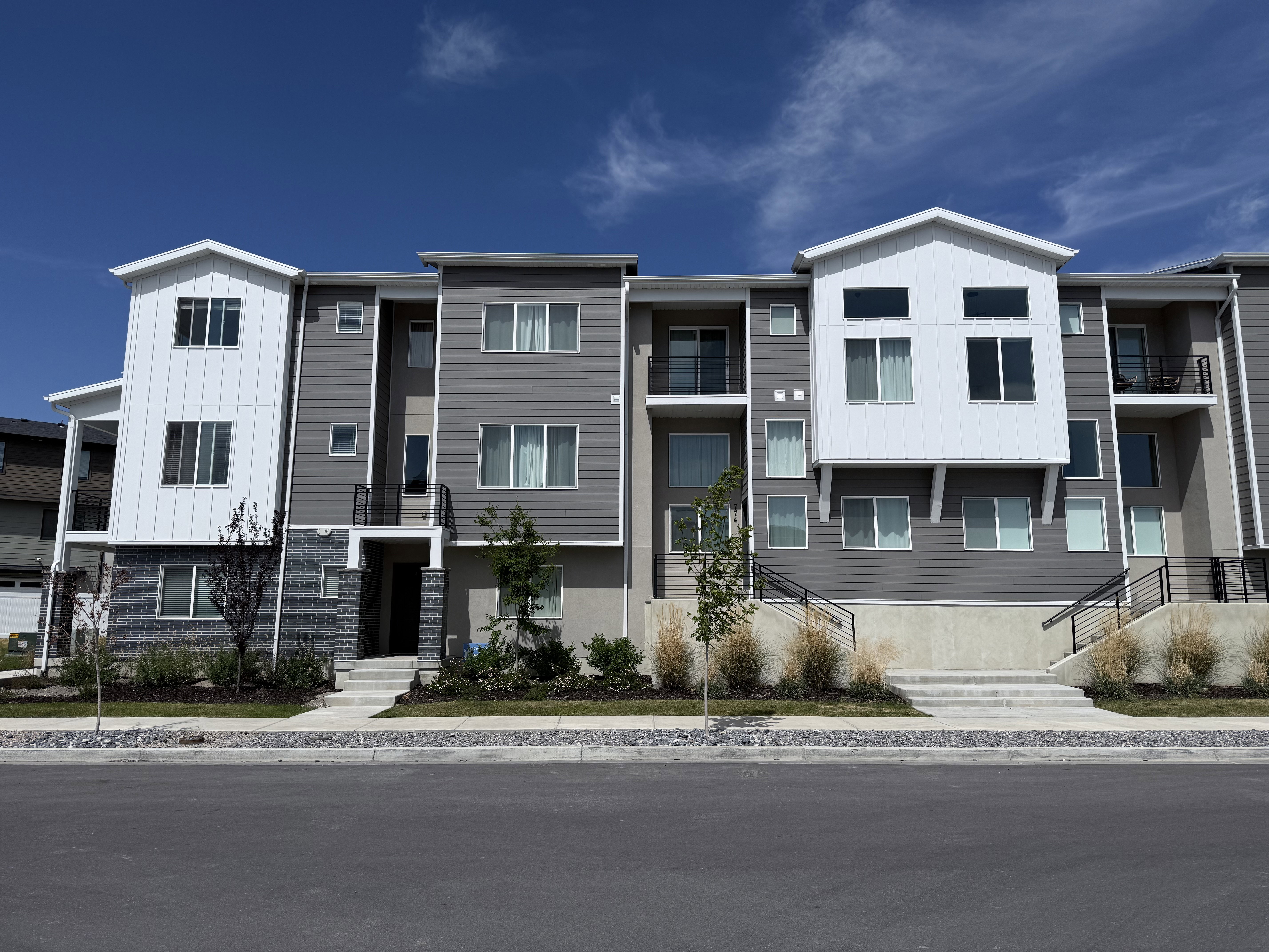 Contemporary multi-story townhome residences featuring varied grey siding and white architectural accents