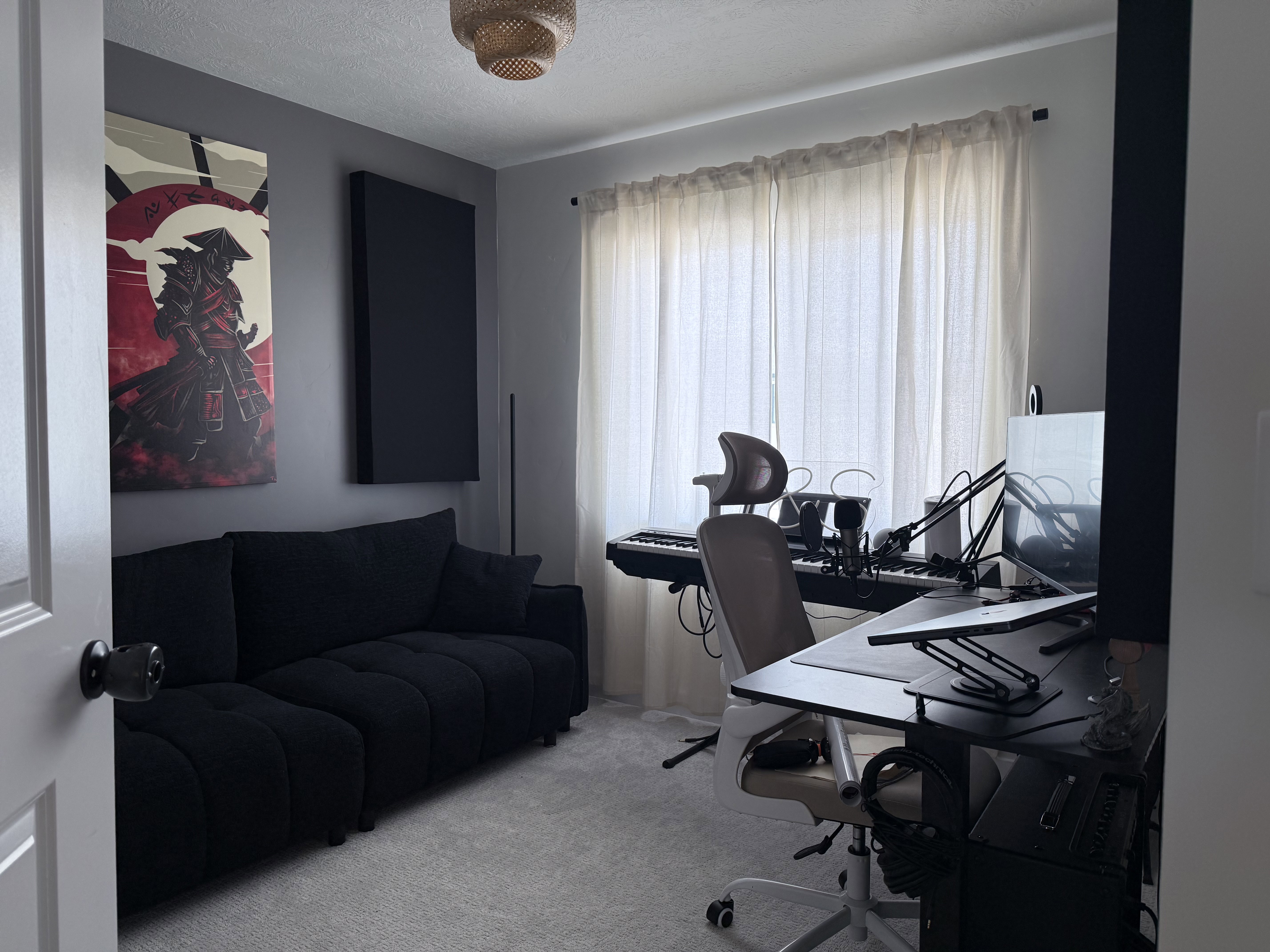 Carpeted interior space with a window featuring sheer curtains, a built-in light fixture, and a neutral wall color