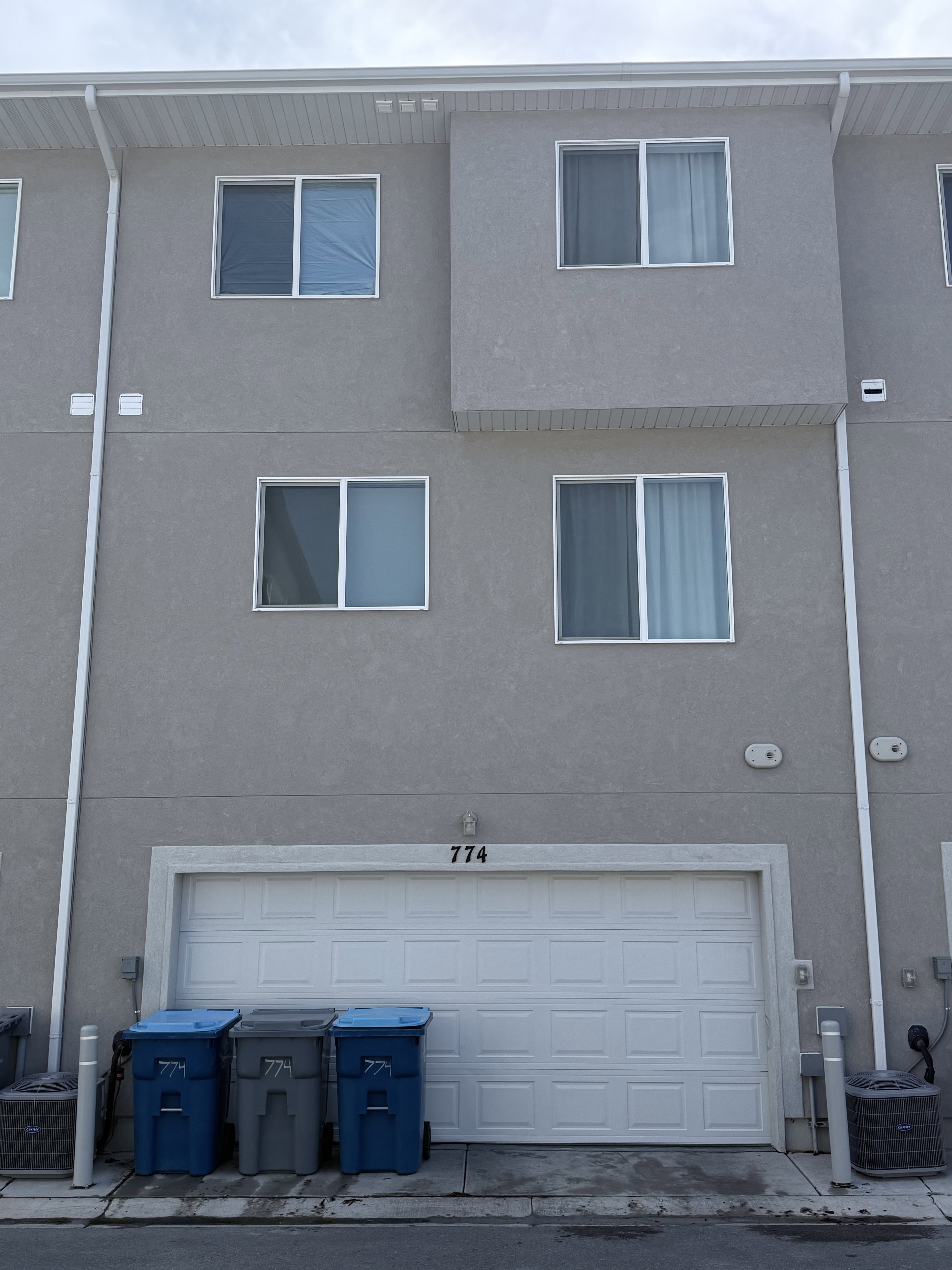 Multi-story stucco exterior with white window frames and a two-car garage