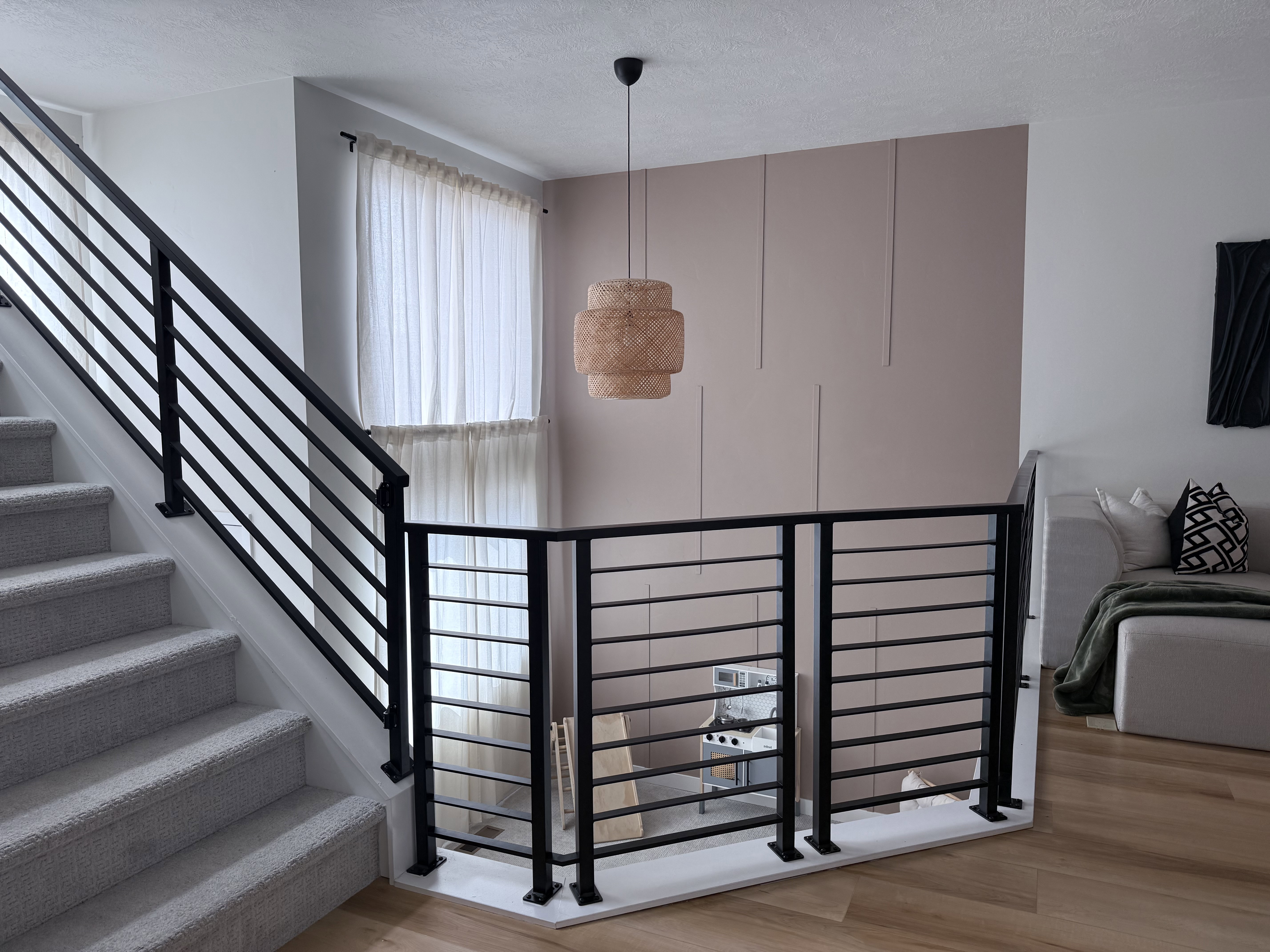 Upper-level landing featuring wood-finish flooring and contemporary black metal horizontal bar railing