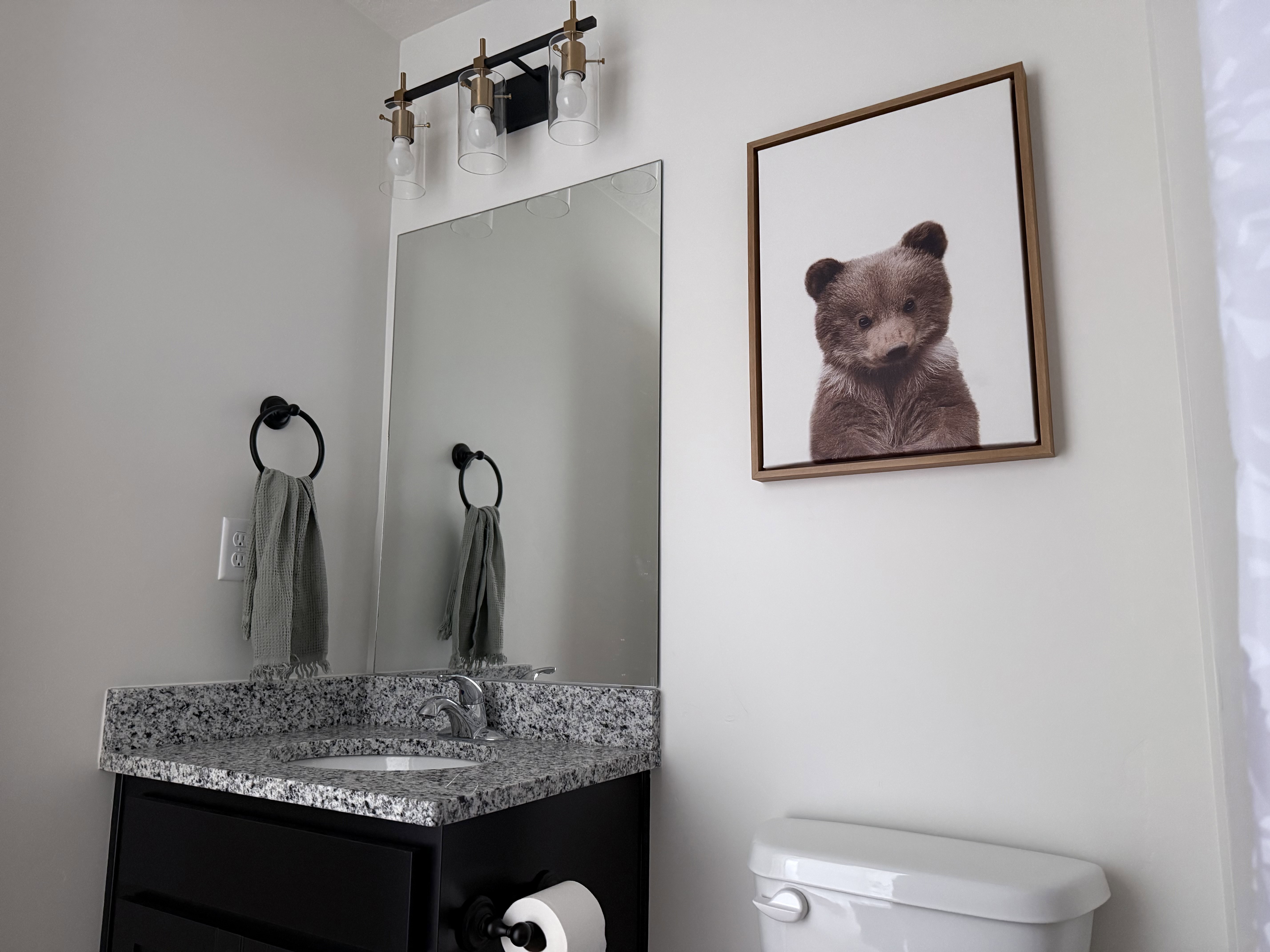 Modern vanity featuring a speckled countertop, undermount sink, and black cabinetry
