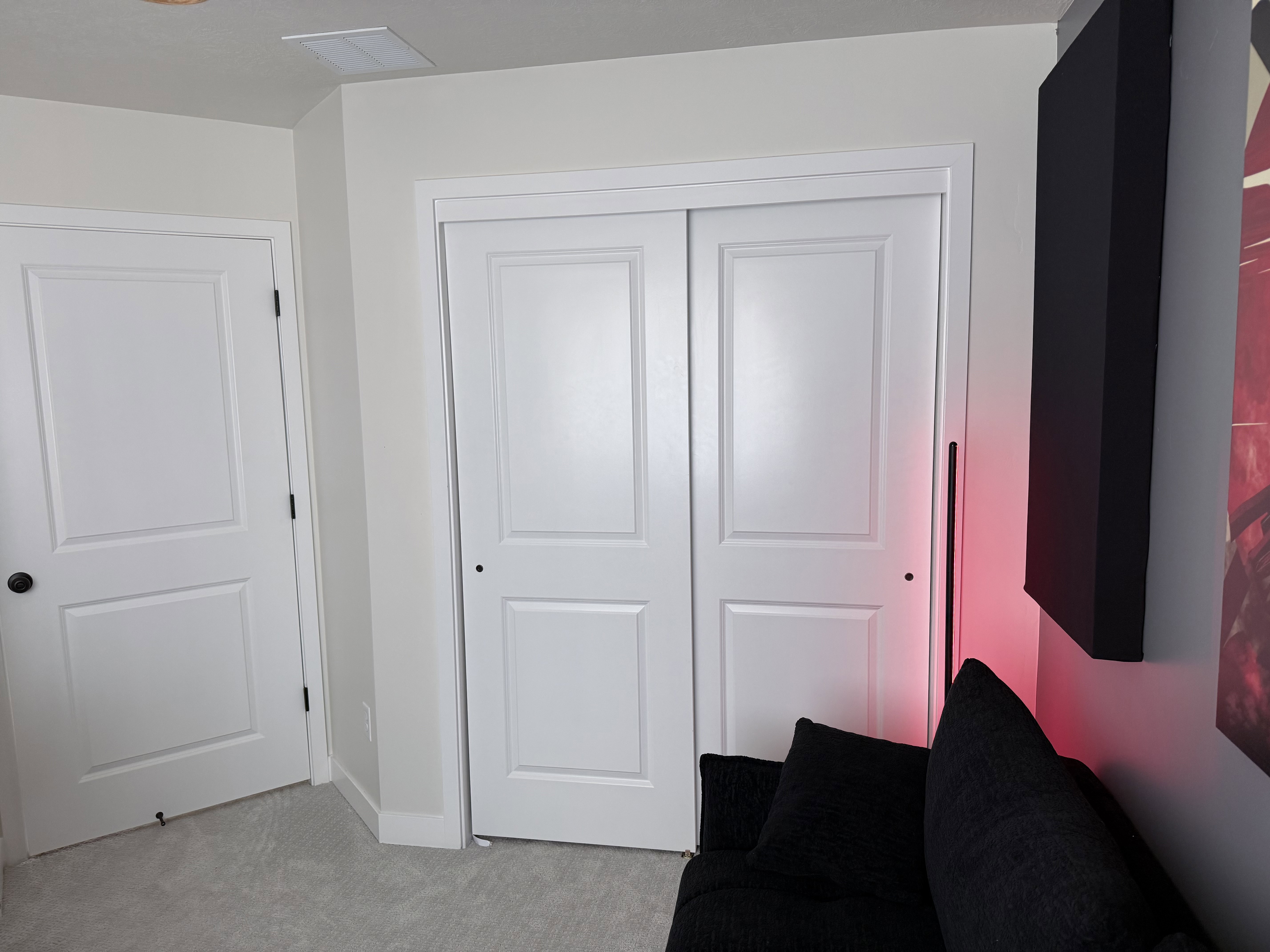 White paneled doors with black hardware, complementing the light-colored walls and soft gray carpeting