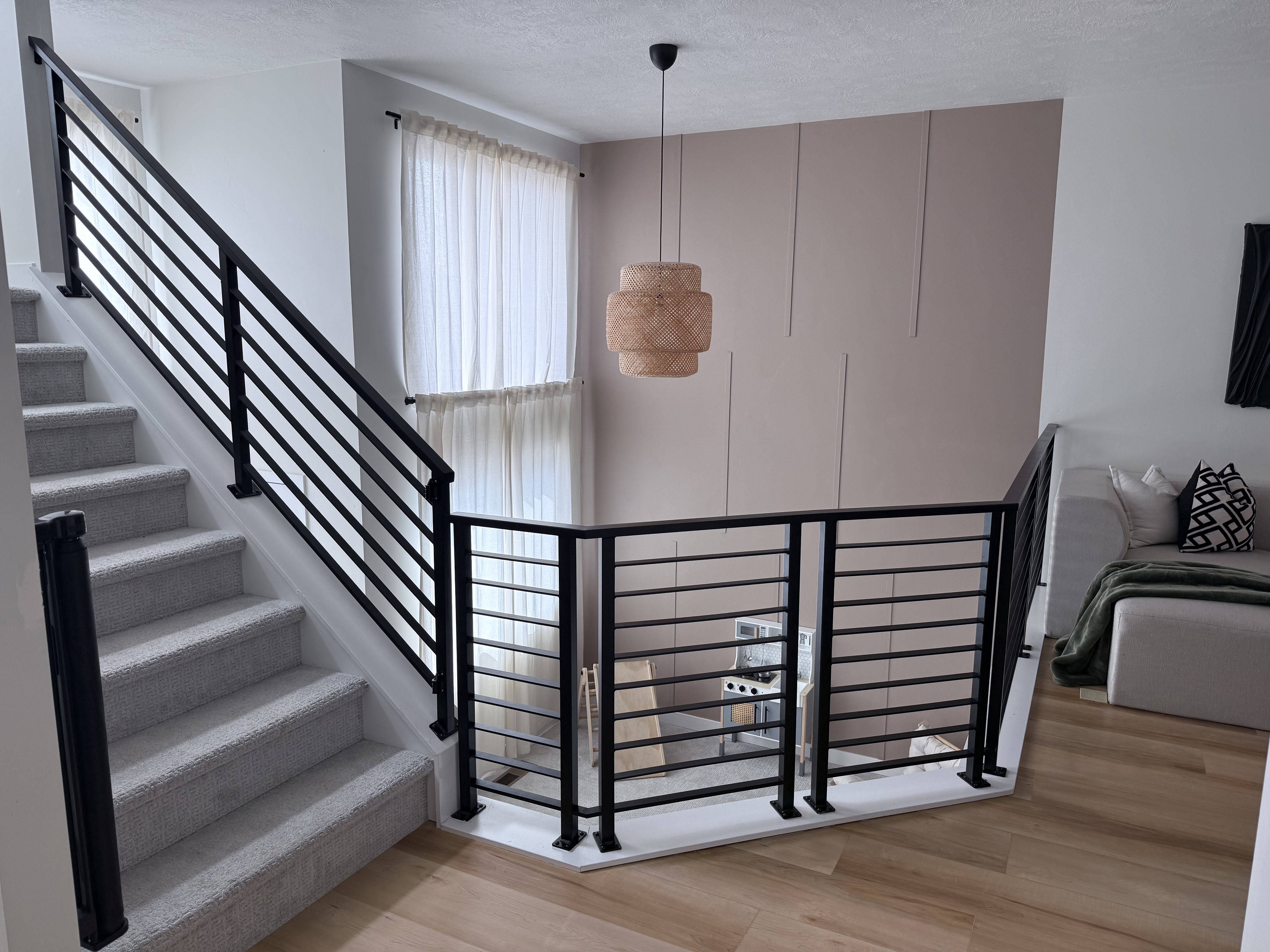 Modern black horizontal bar railings frame the staircase and upper landing
