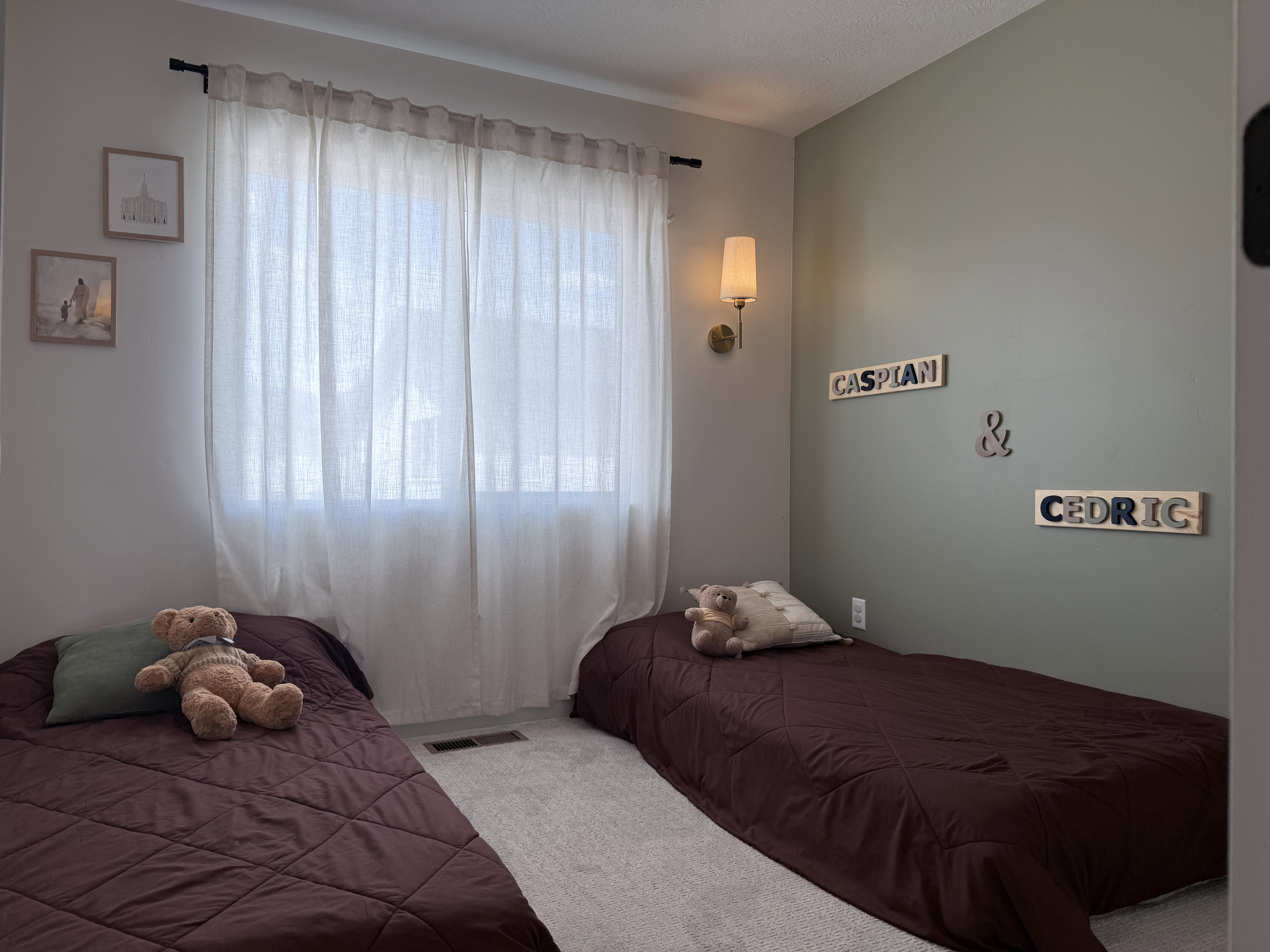 Bedroom featuring light gray wall paint, an accent wall with sage green paint, and light-colored carpet flooring