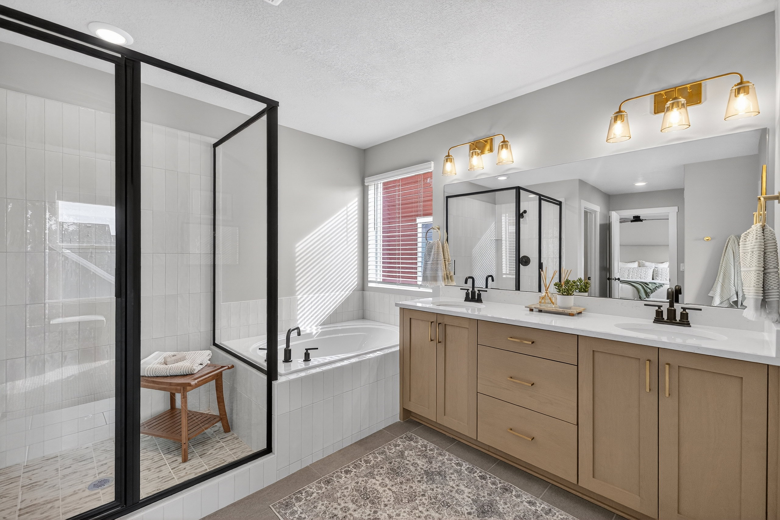 Contemporary bathroom featuring a spacious walk-in shower with black-framed glass, a built-in soaking tub, and a dual vanity with light-colored cabinetry