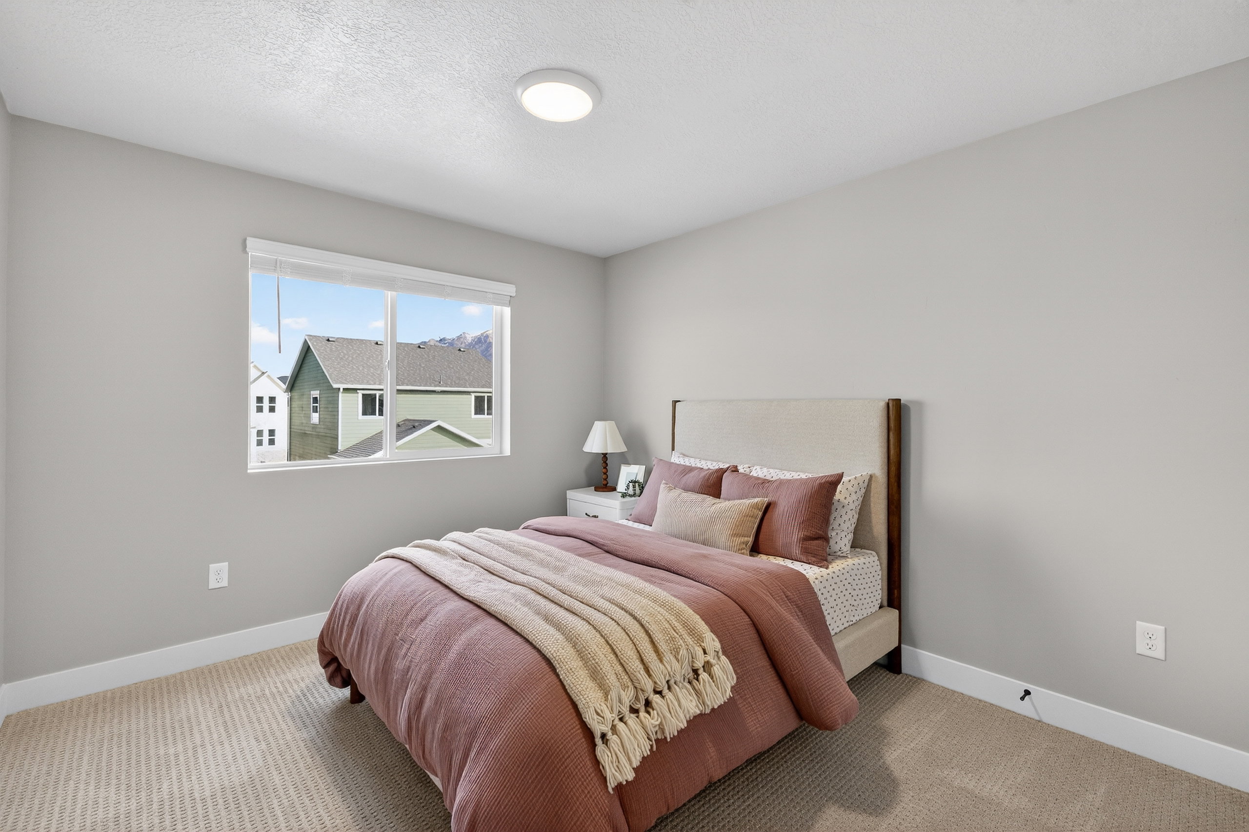 Spacious room featuring neutral carpeting, a large window, and light gray walls
