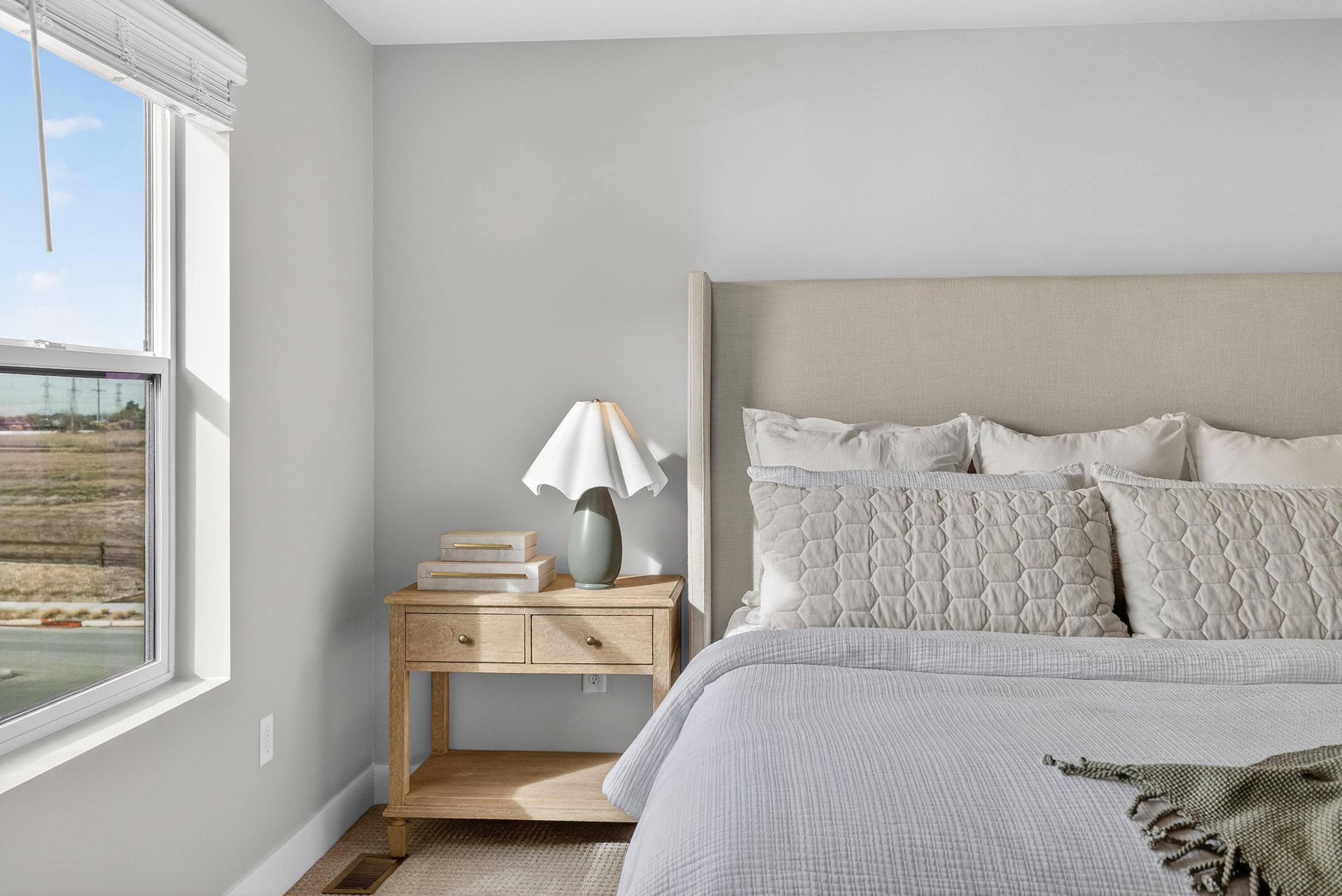Bedroom featuring light gray walls, a window with white blinds, and wood-finish flooring