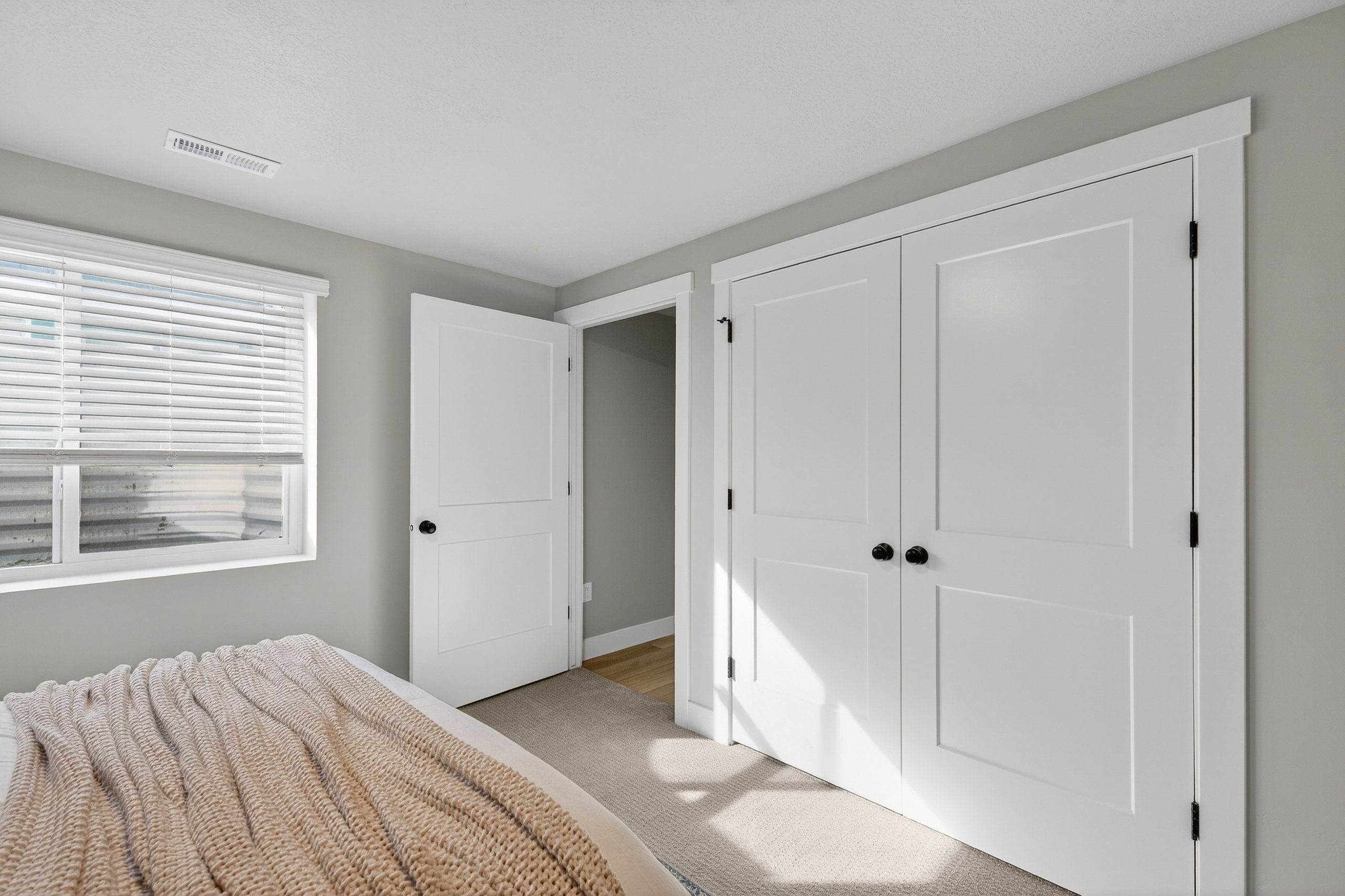 Bedroom featuring a window with blinds, light gray walls, and carpet flooring