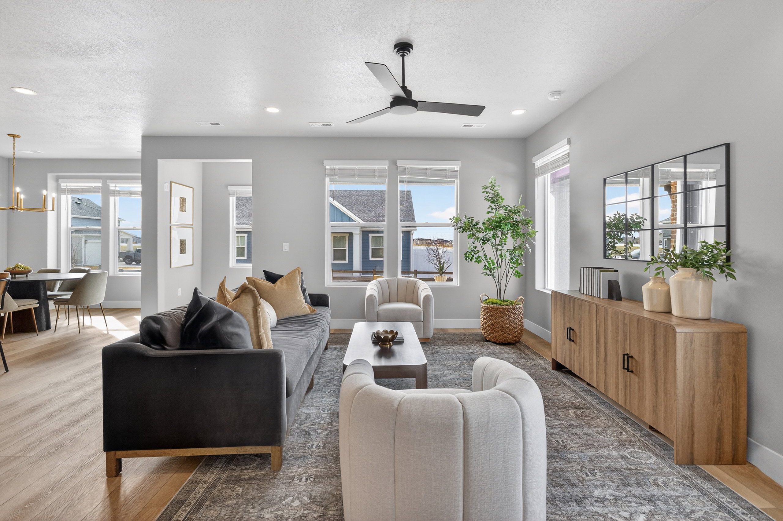 Spacious living area featuring light wood-finish flooring in the dining space, a modern ceiling fan, recessed lighting, and multiple windows providing natural light