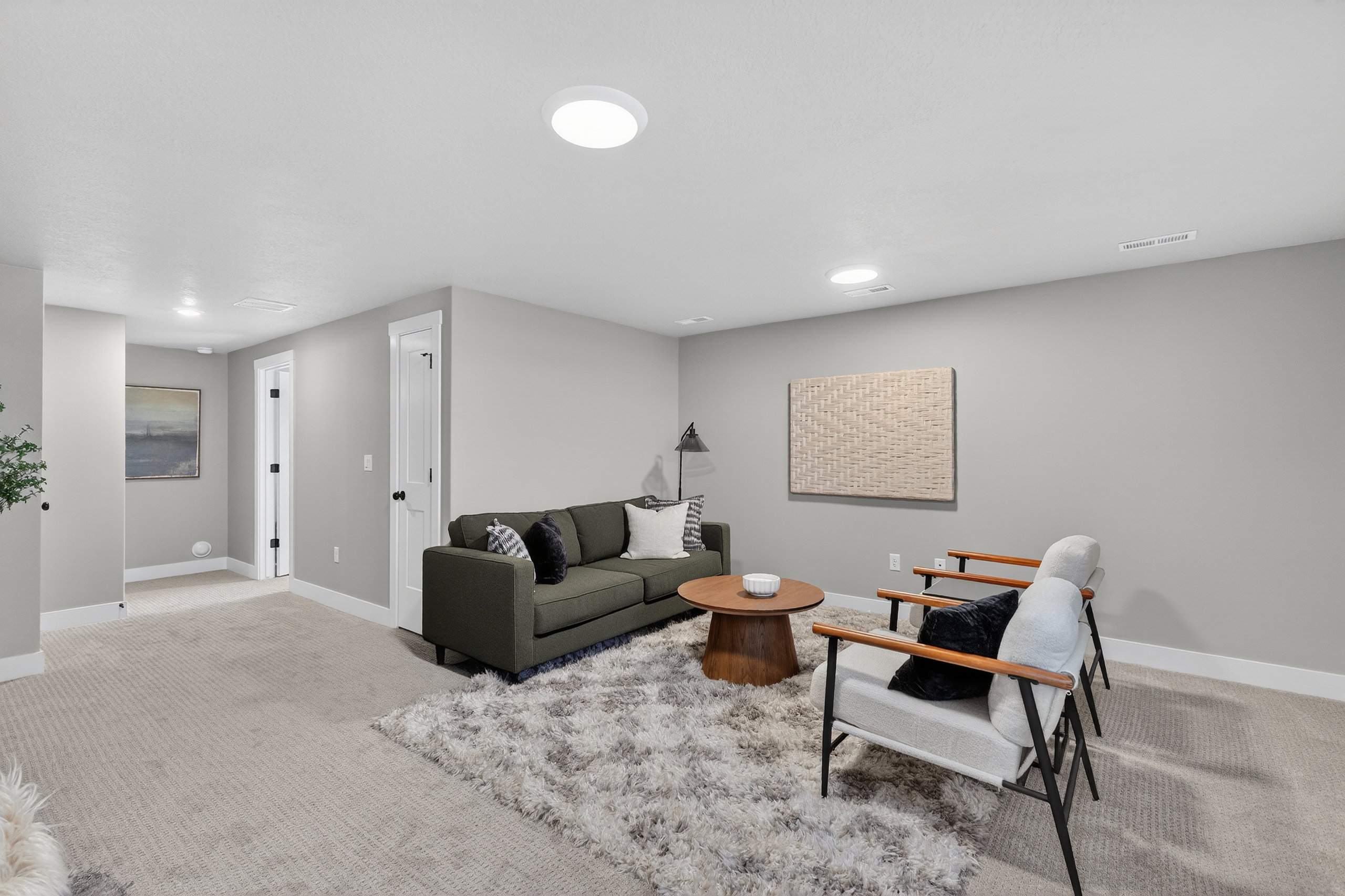 Spacious carpeted room featuring light gray walls, white trim, recessed lighting, and white paneled doors with black hardware