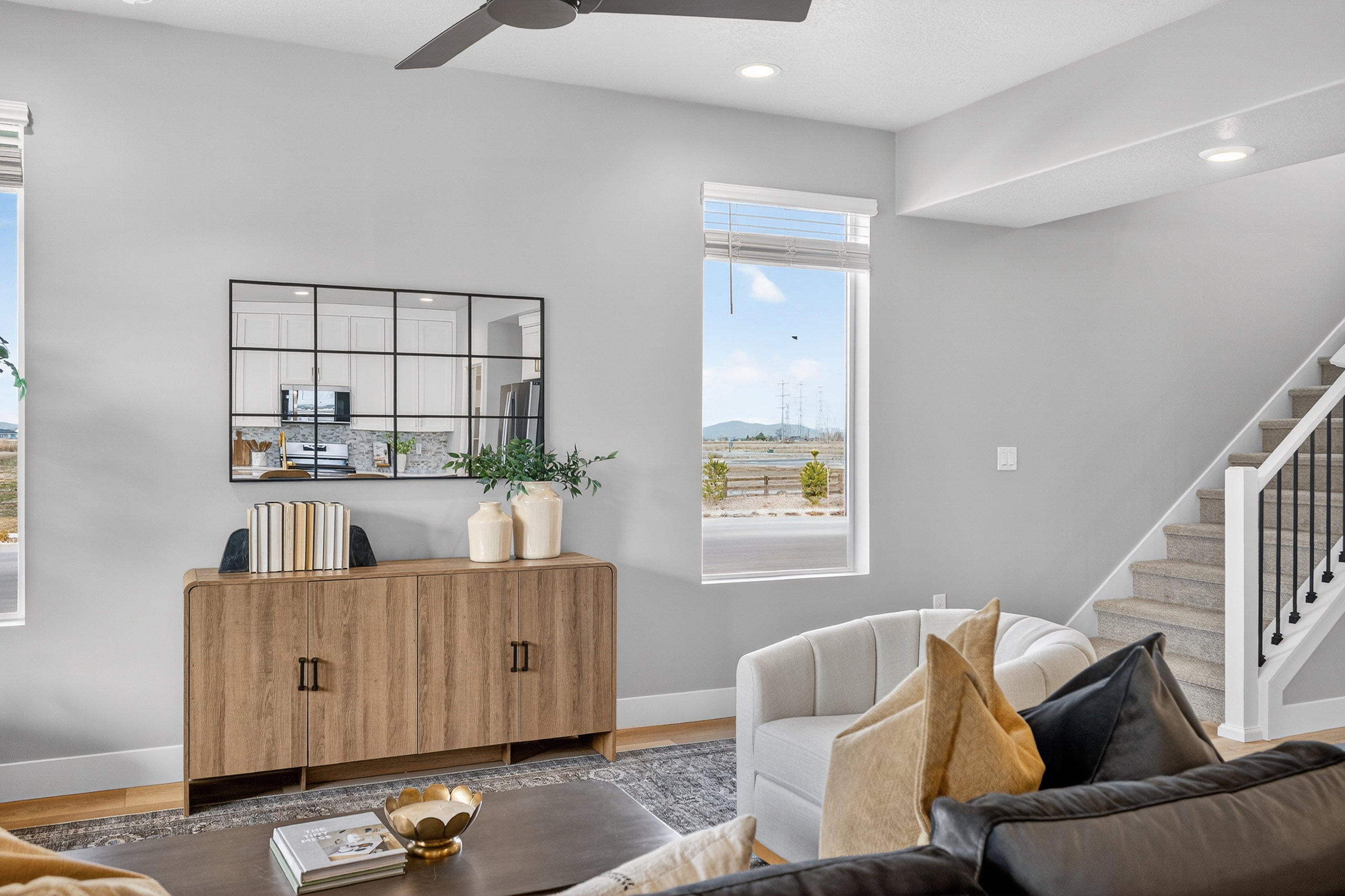 Spacious living area featuring light wood-finish flooring and a staircase with a black metal spindle railing