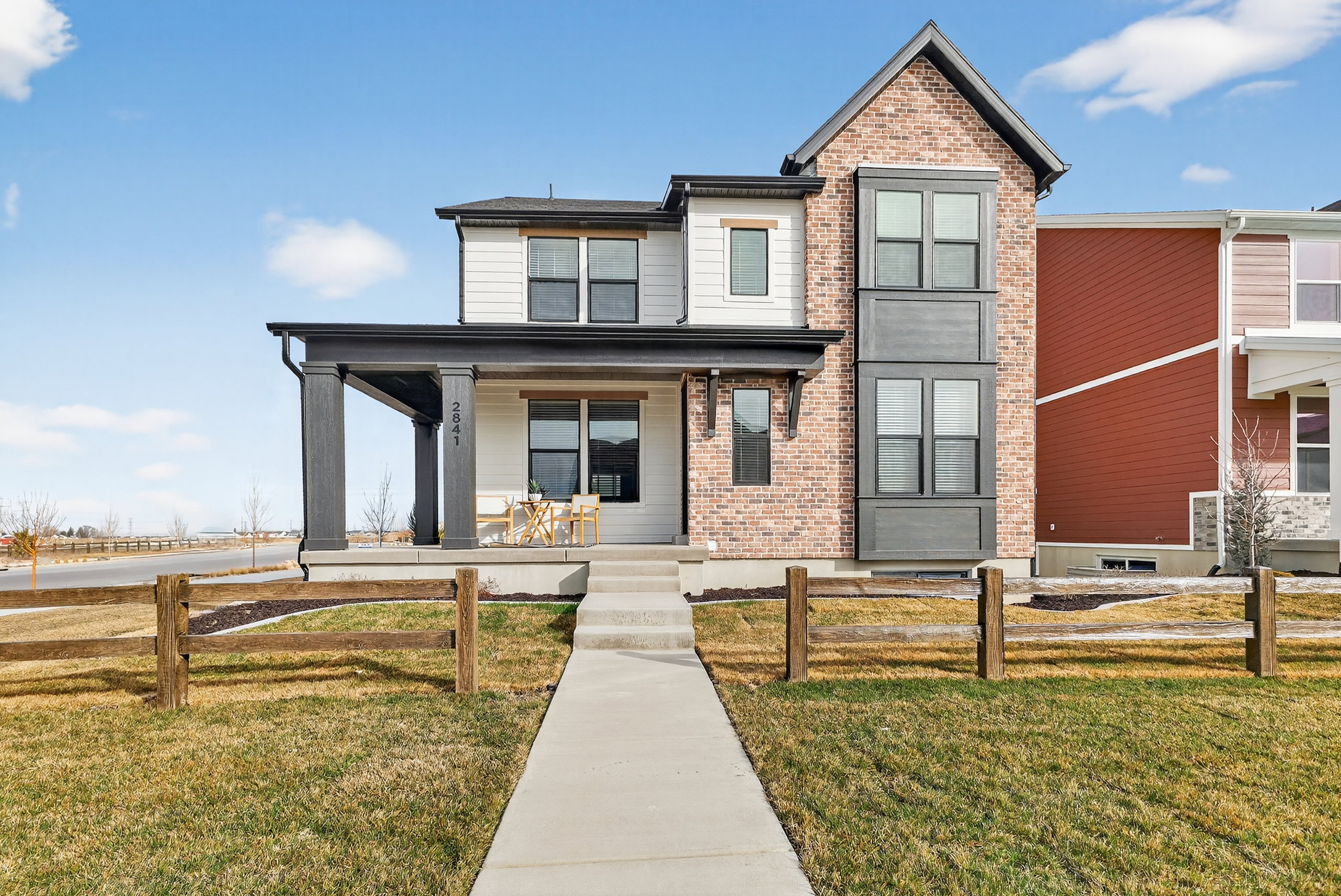Modern facade featuring a covered entry, brick accents, and vertical siding