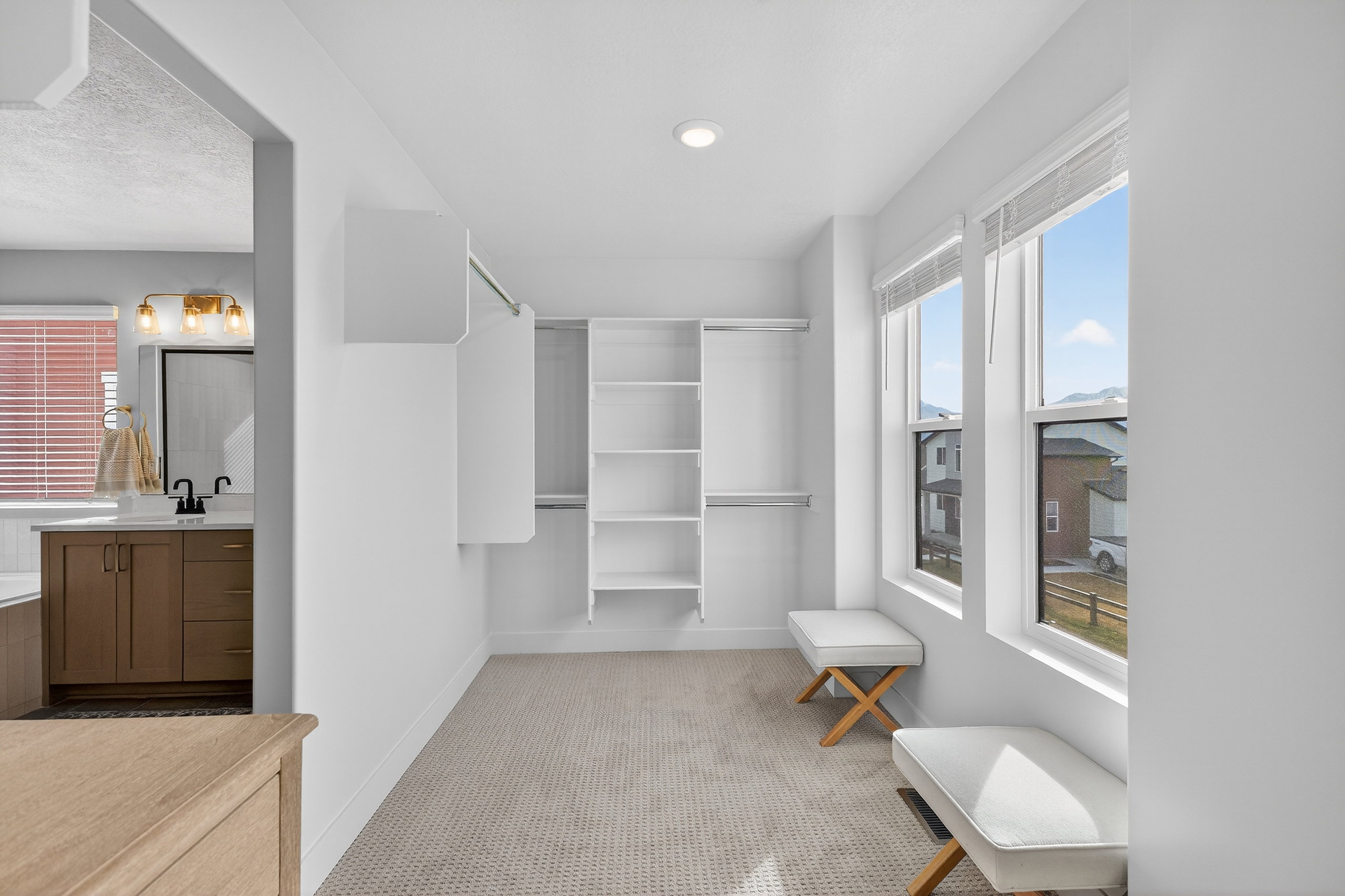 Spacious walk-in closet featuring built-in shelving, hanging rods, and twin double-hung windows