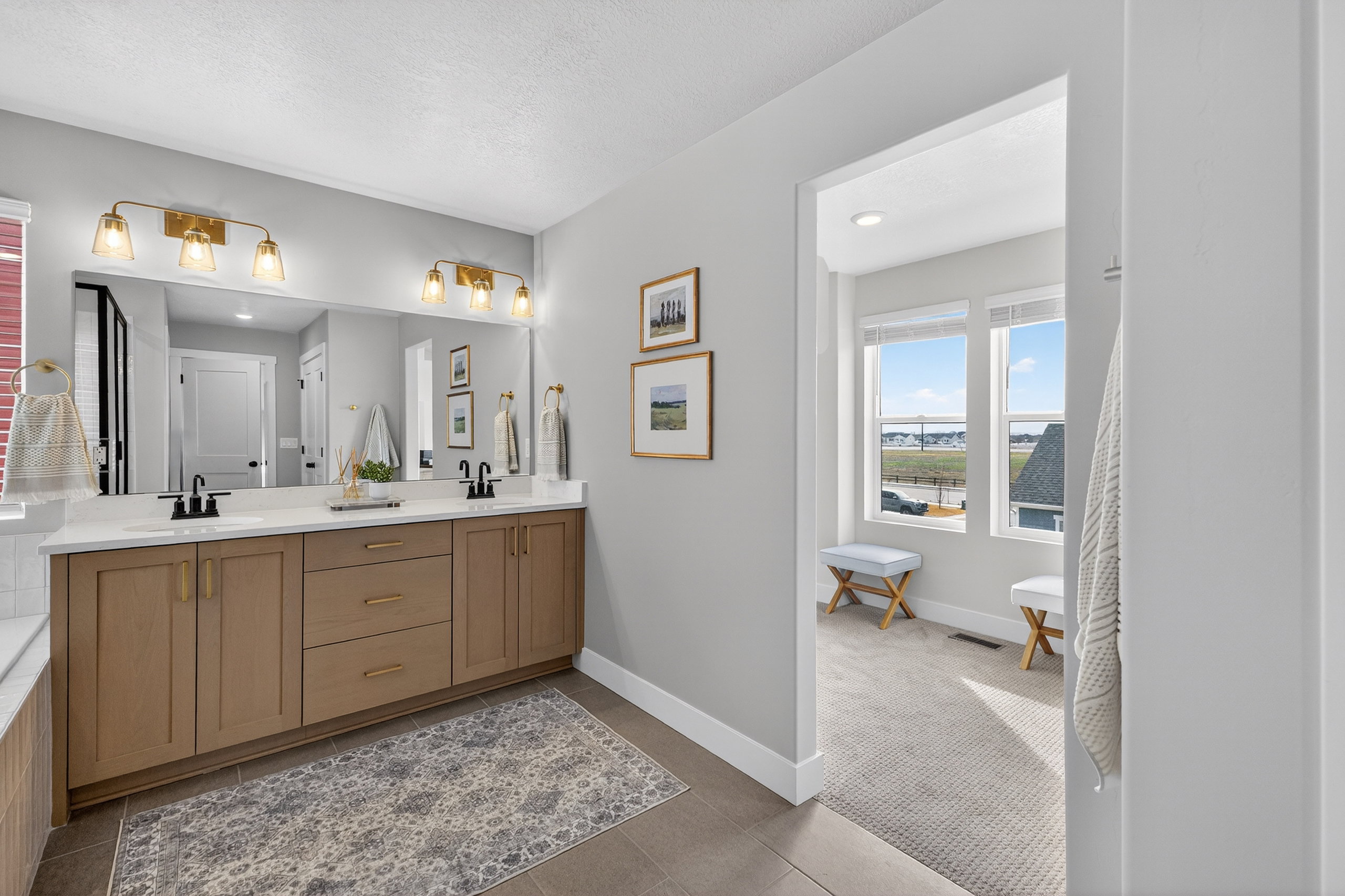 Double vanity featuring light wood cabinetry, white countertops, and black fixtures
