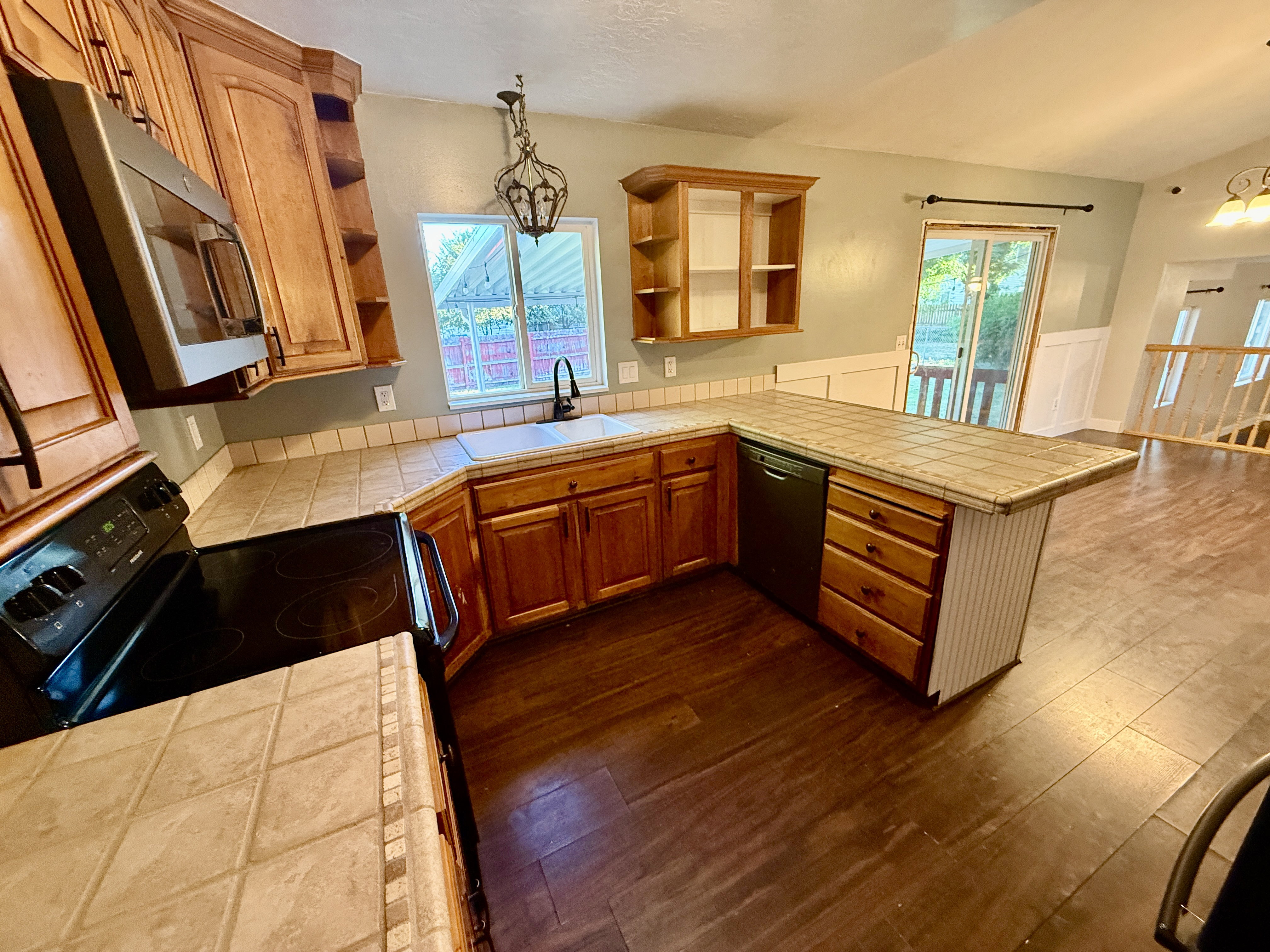 Kitchen featuring wood-finish flooring, wood cabinetry, tile countertops, and a built-in microwave and oven