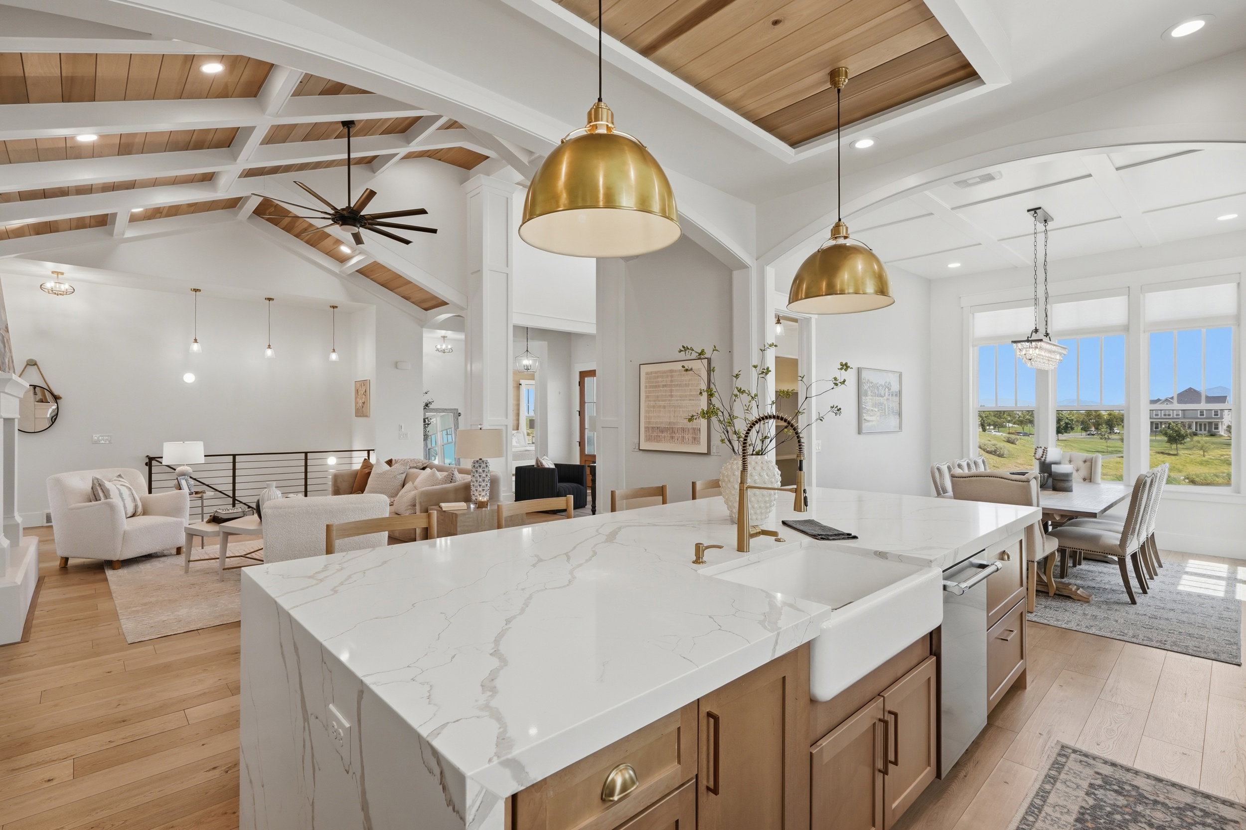 Gourmet kitchen island featuring a farmhouse sink, integrated dishwasher, and brass-toned pendant lighting