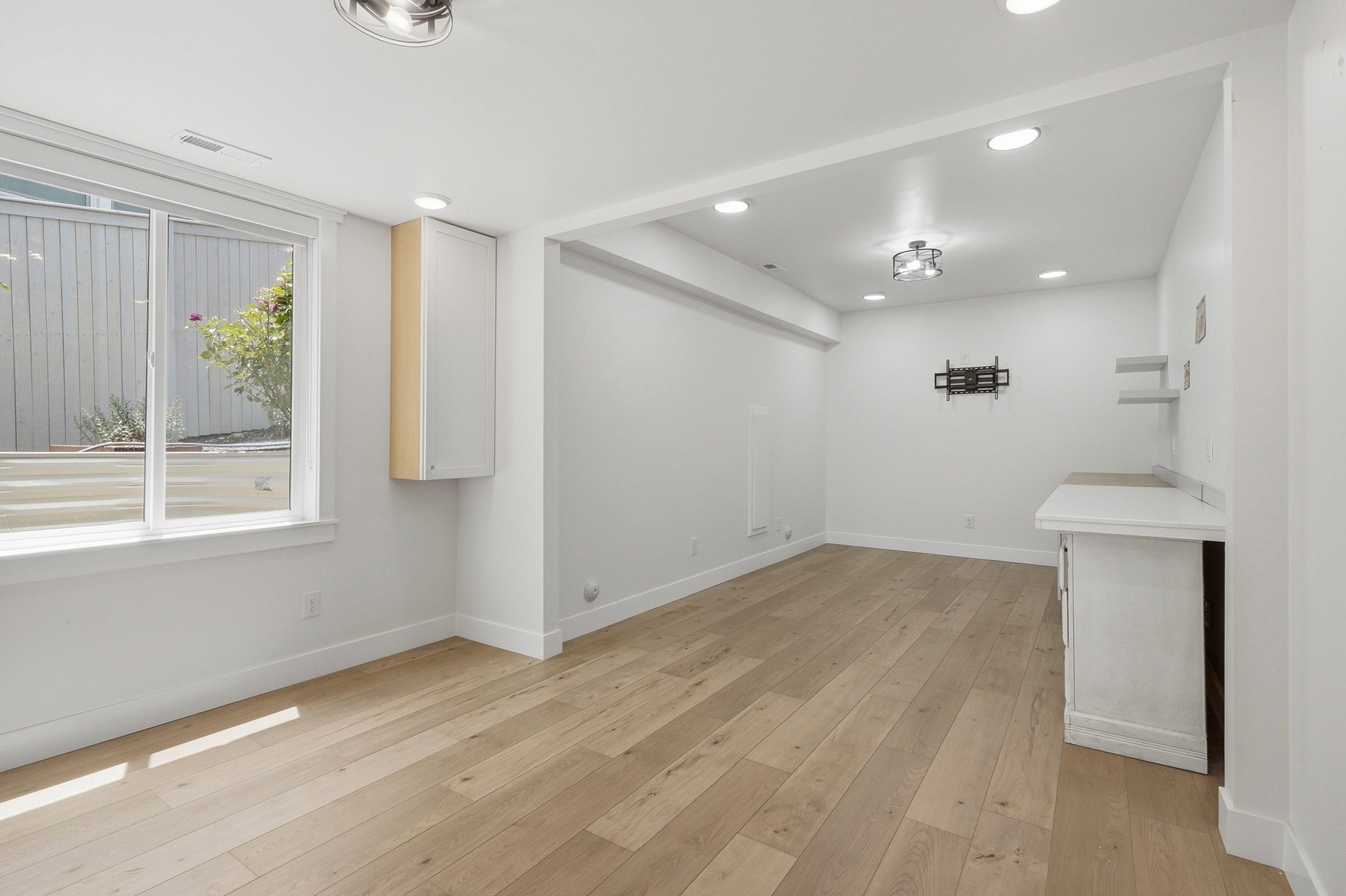 Expansive room featuring wood-finish flooring, recessed lighting, and a dual-pane window