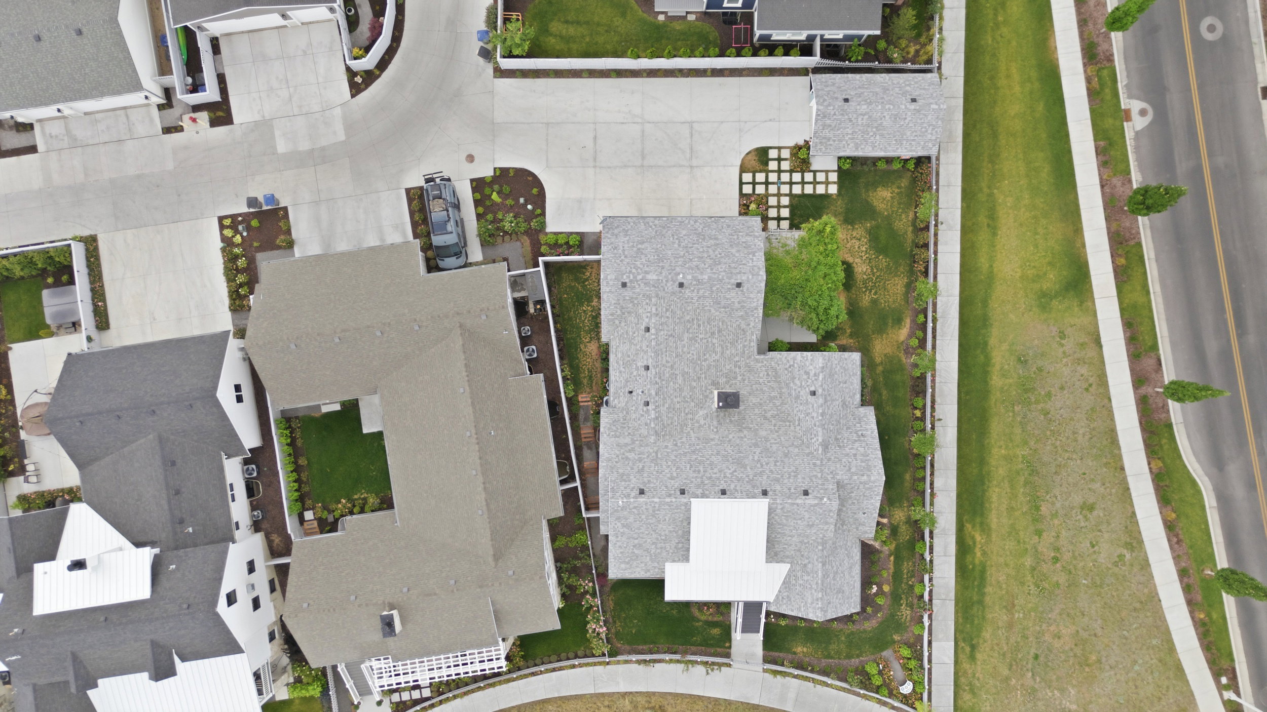 Aerial perspective showcasing a property with a multi-gabled roofline, concrete driveway, and a landscaped front yard