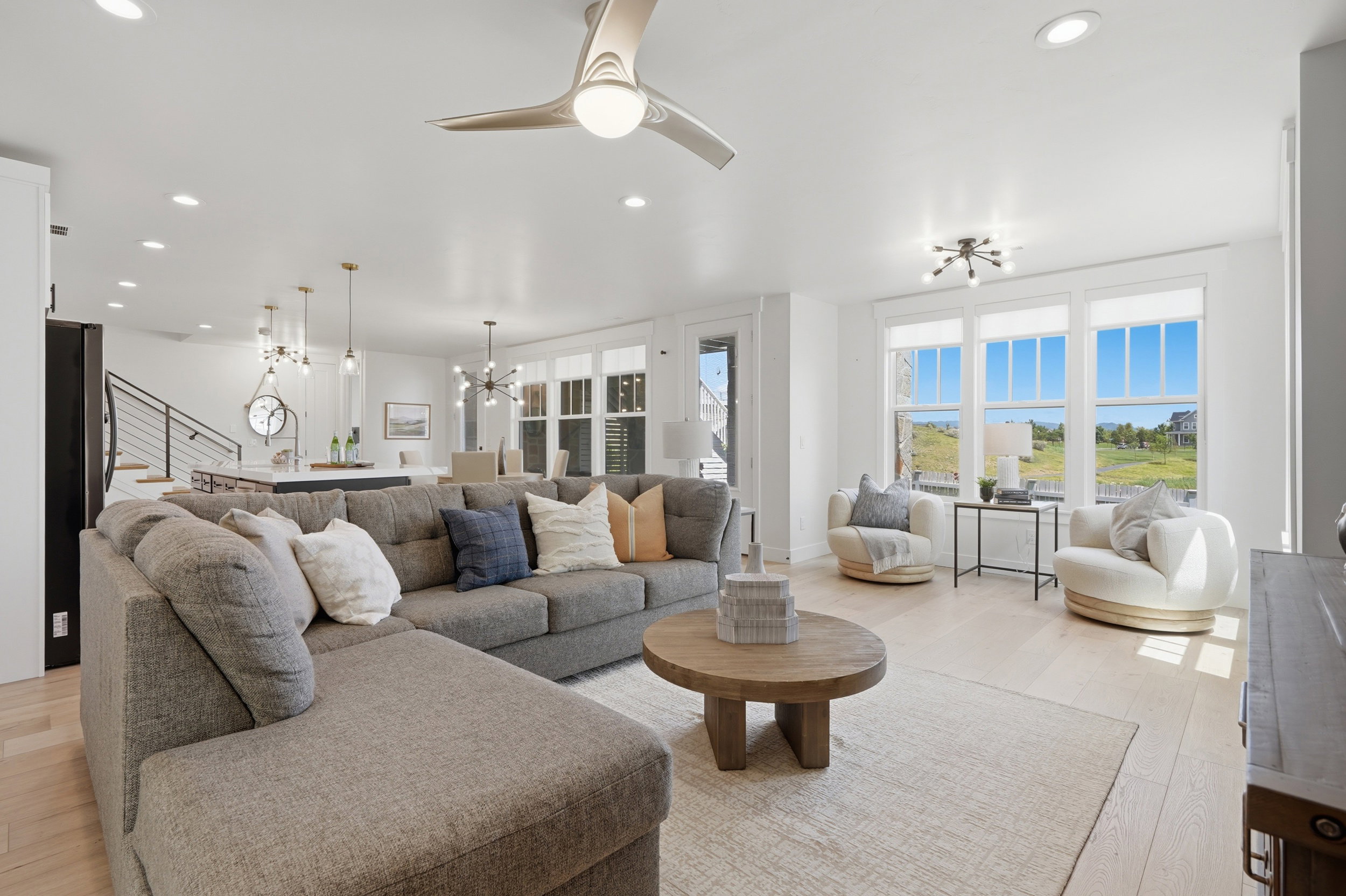 Open-concept living space with light wood-finish flooring, recessed lighting, and large windows