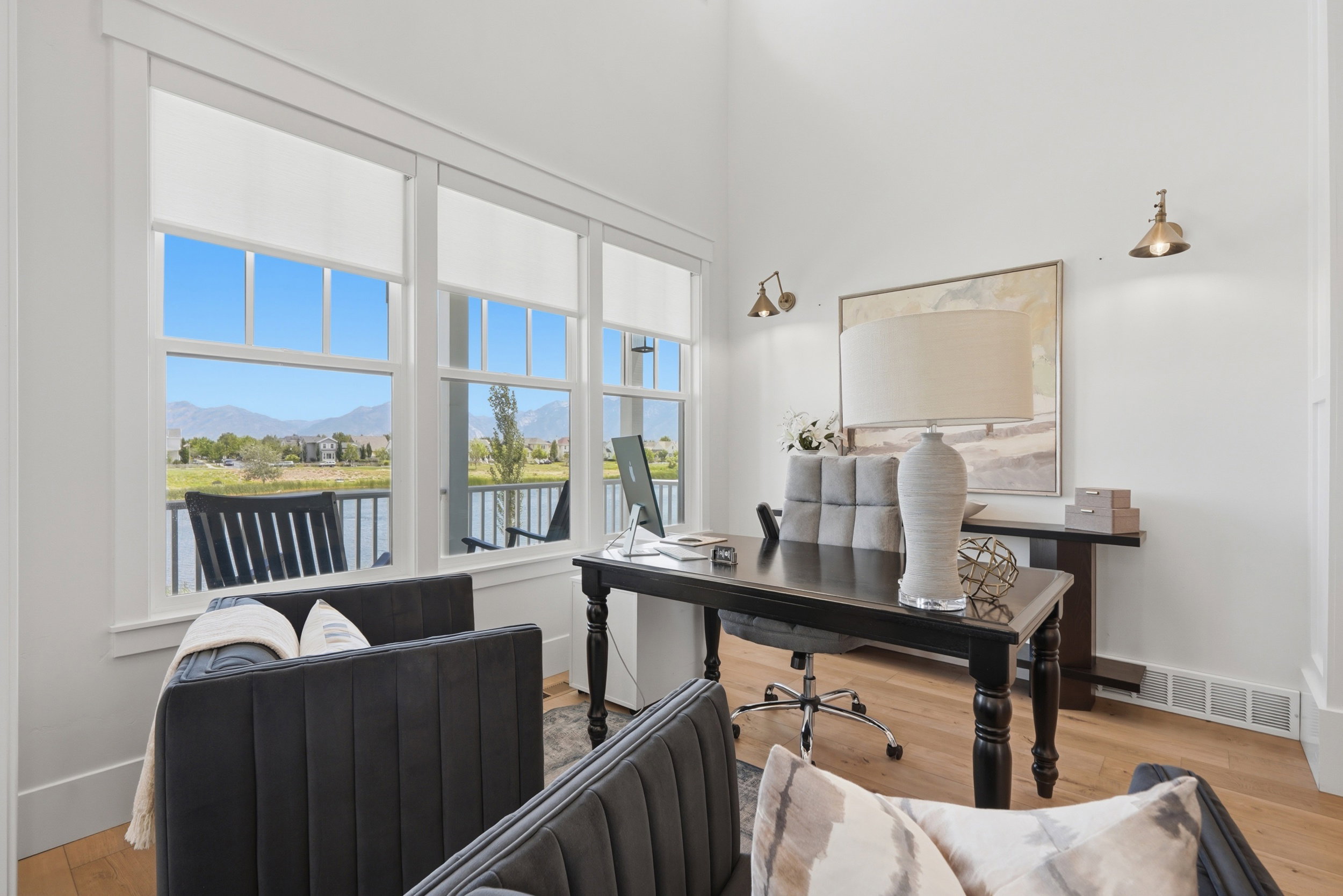 Bright interior space featuring multiple windows with roller shades, light wood-finish flooring, and white walls