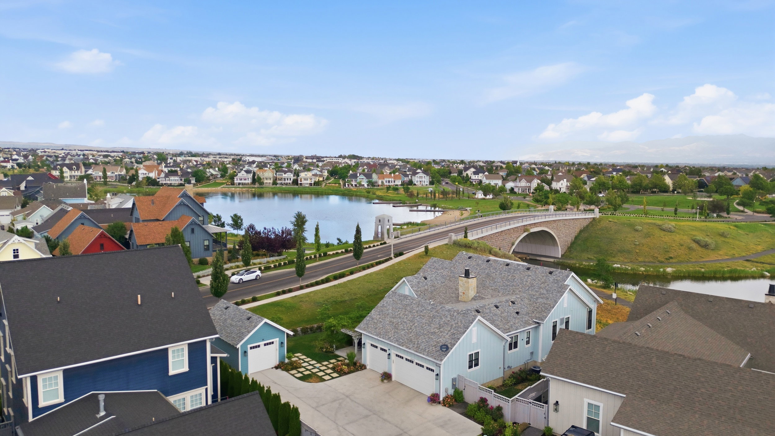 Residential area featuring a central lake, a stone arch bridge, and surrounding green spaces