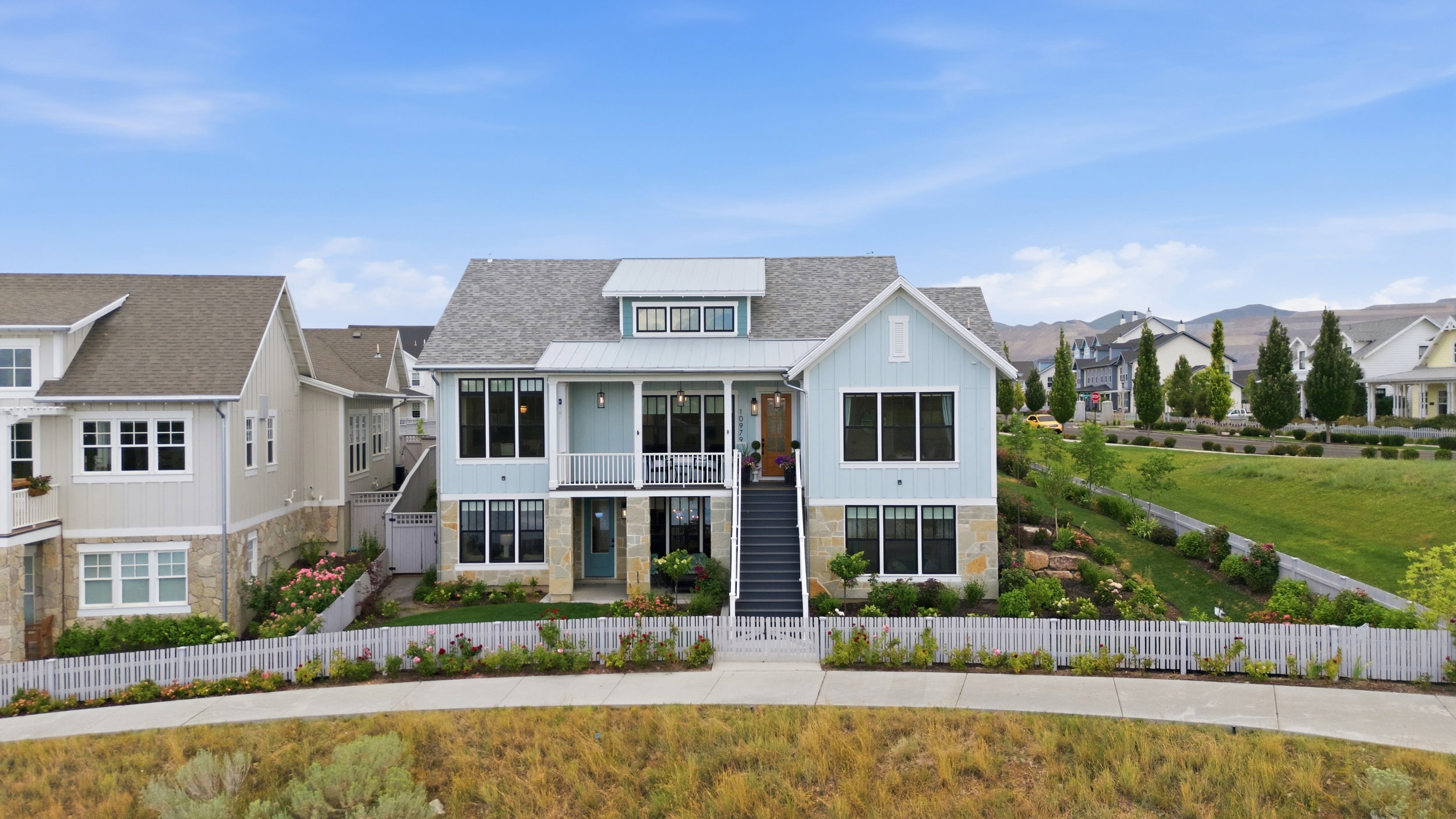 Light blue siding residence featuring a covered balcony, multiple gables, a dormer window, and an exterior staircase
