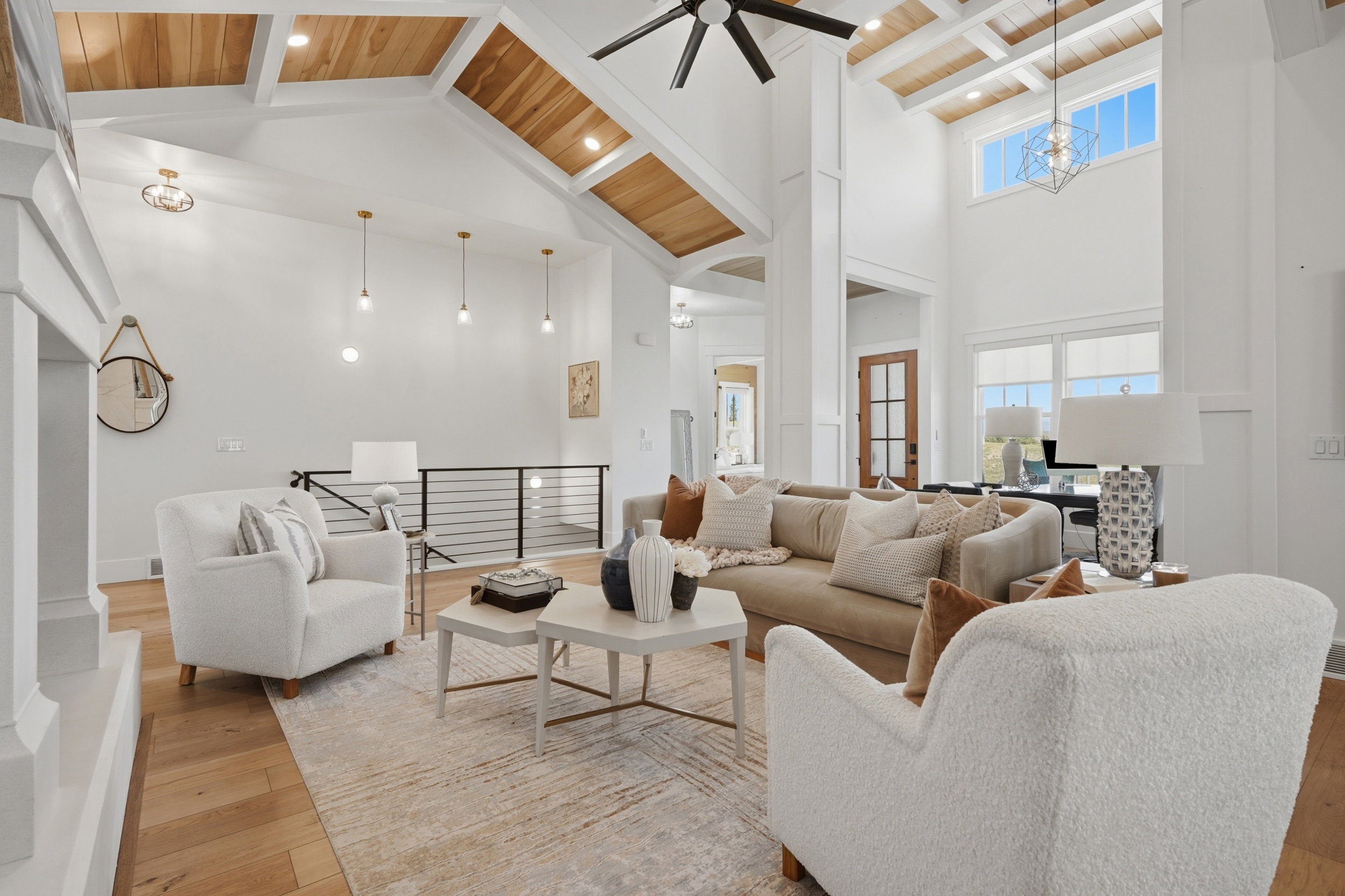 Spacious living area featuring a vaulted wood-paneled ceiling, light wood-finish flooring, and crisp white walls