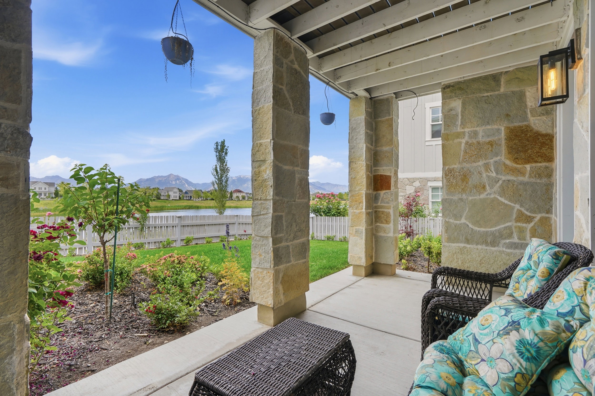 Covered patio featuring stone-clad pillars, concrete flooring, and a mounted exterior light fixture