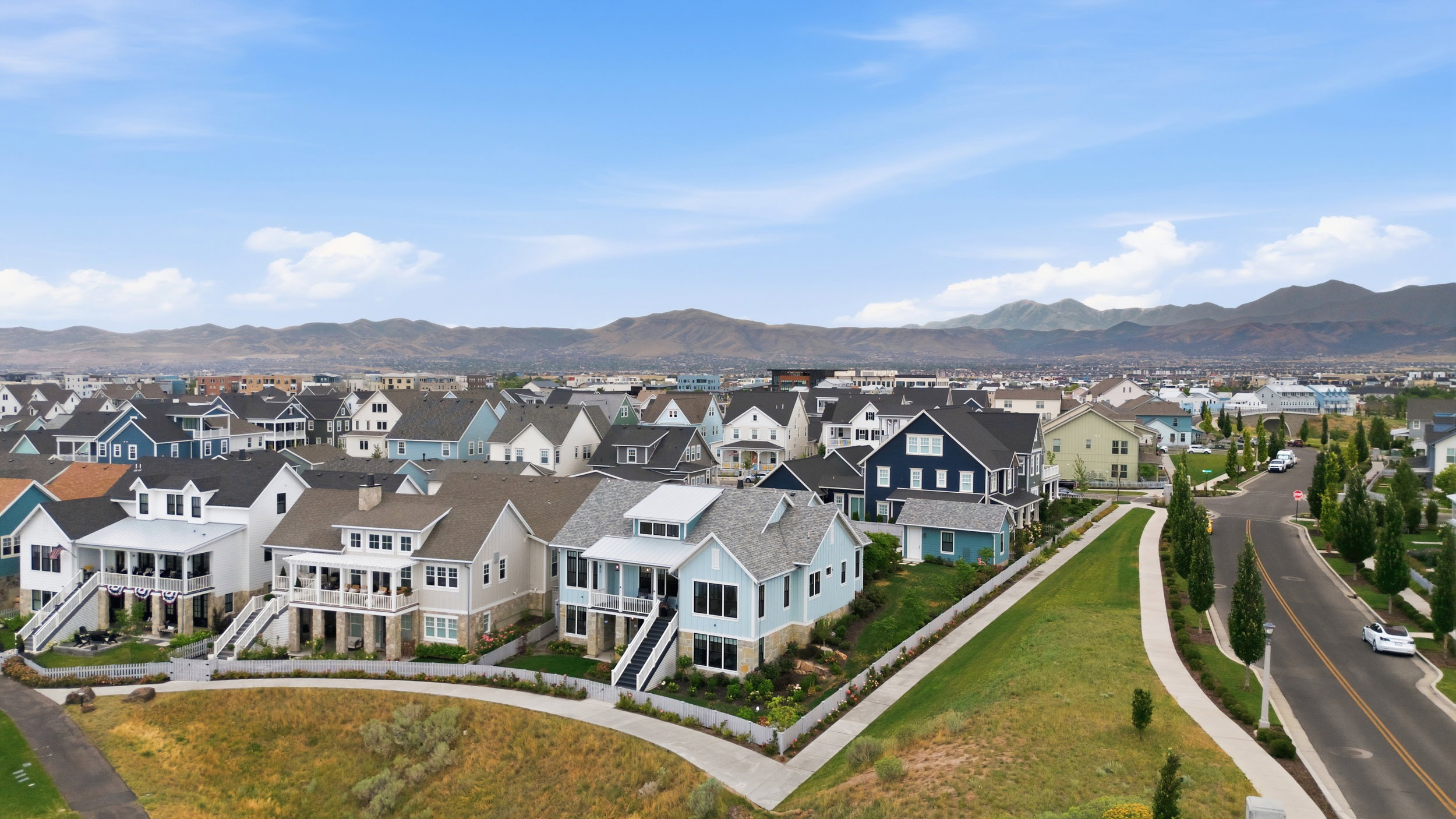 Neighborhood street featuring a variety of architectural styles, a paved street, and landscaped sidewalks