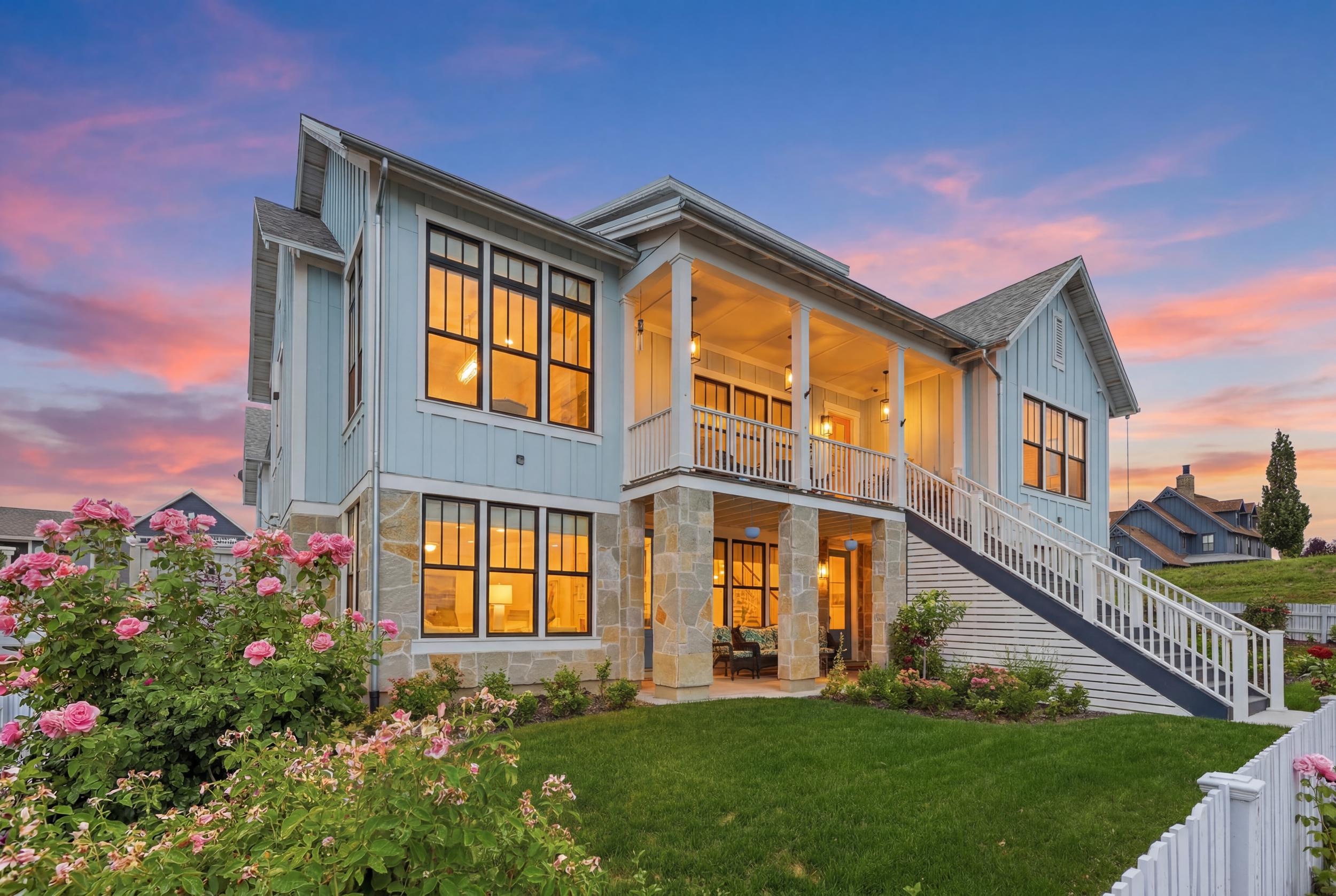 Multi-level residence featuring light blue siding, a stone facade, and extensive outdoor living spaces