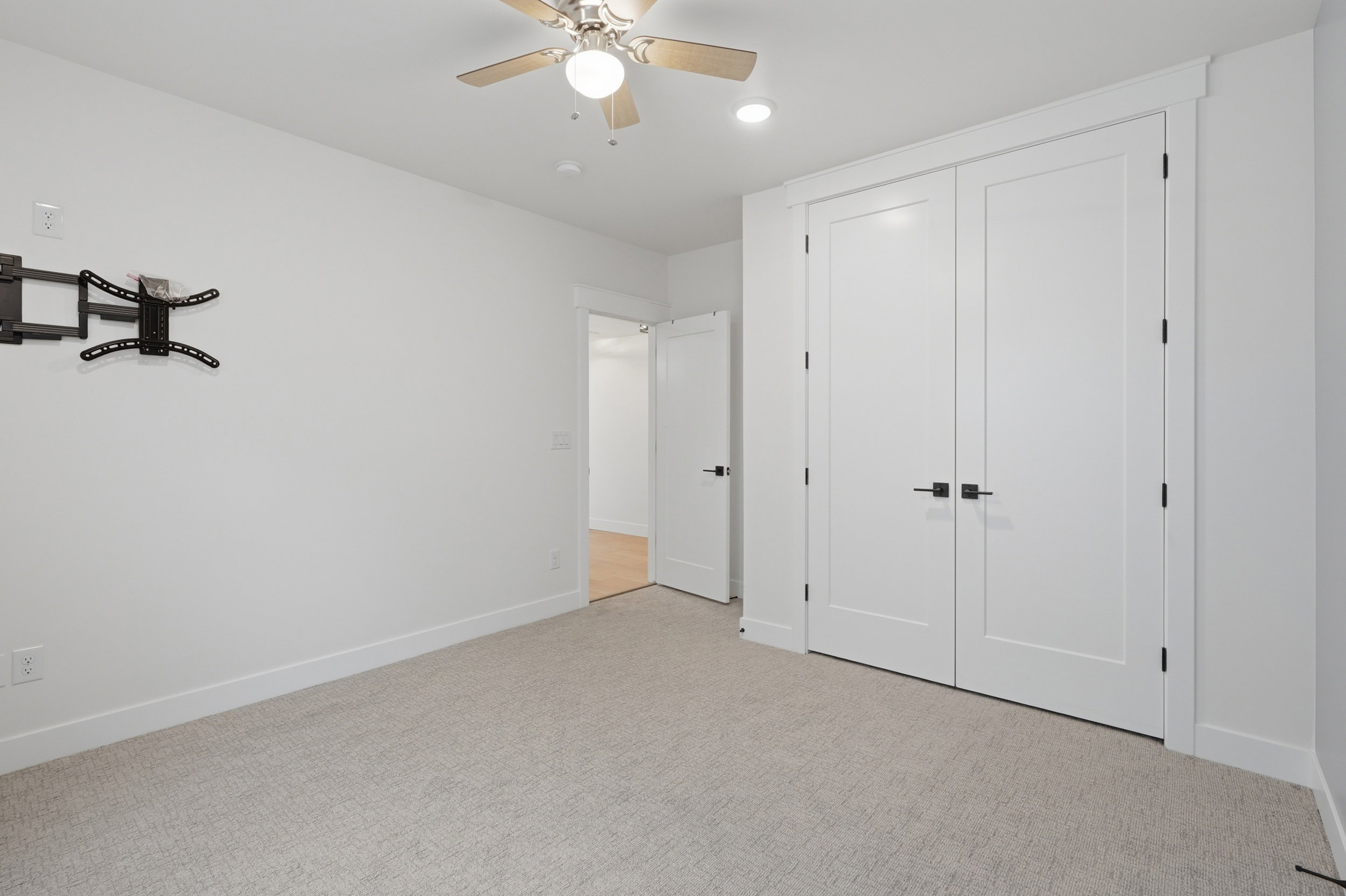 Interior space featuring light-colored carpet flooring, white walls, and a ceiling fan with integrated lighting