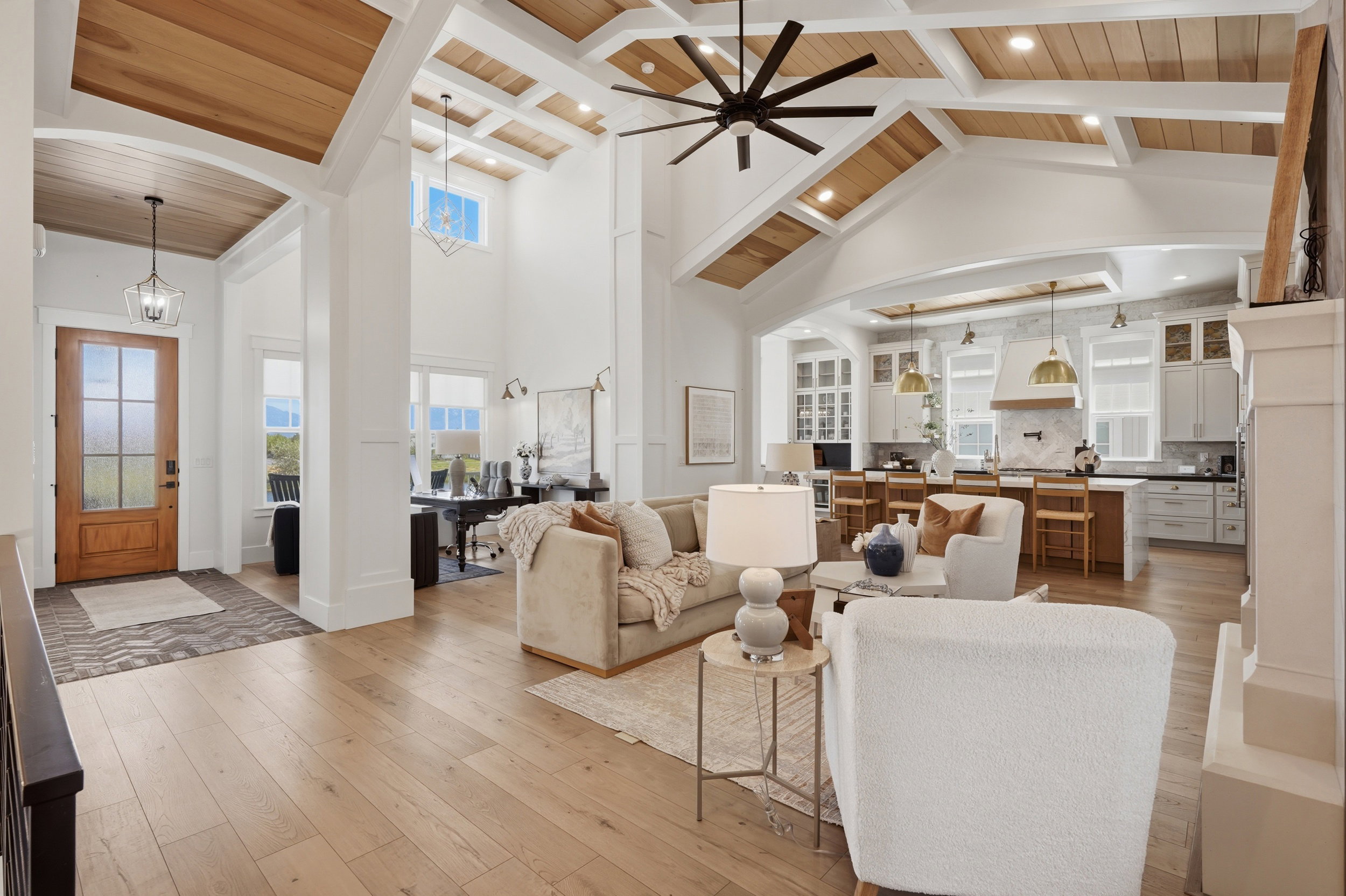 Vaulted ceilings with wood-finish accents, light wood-finish flooring, and a stone fireplace