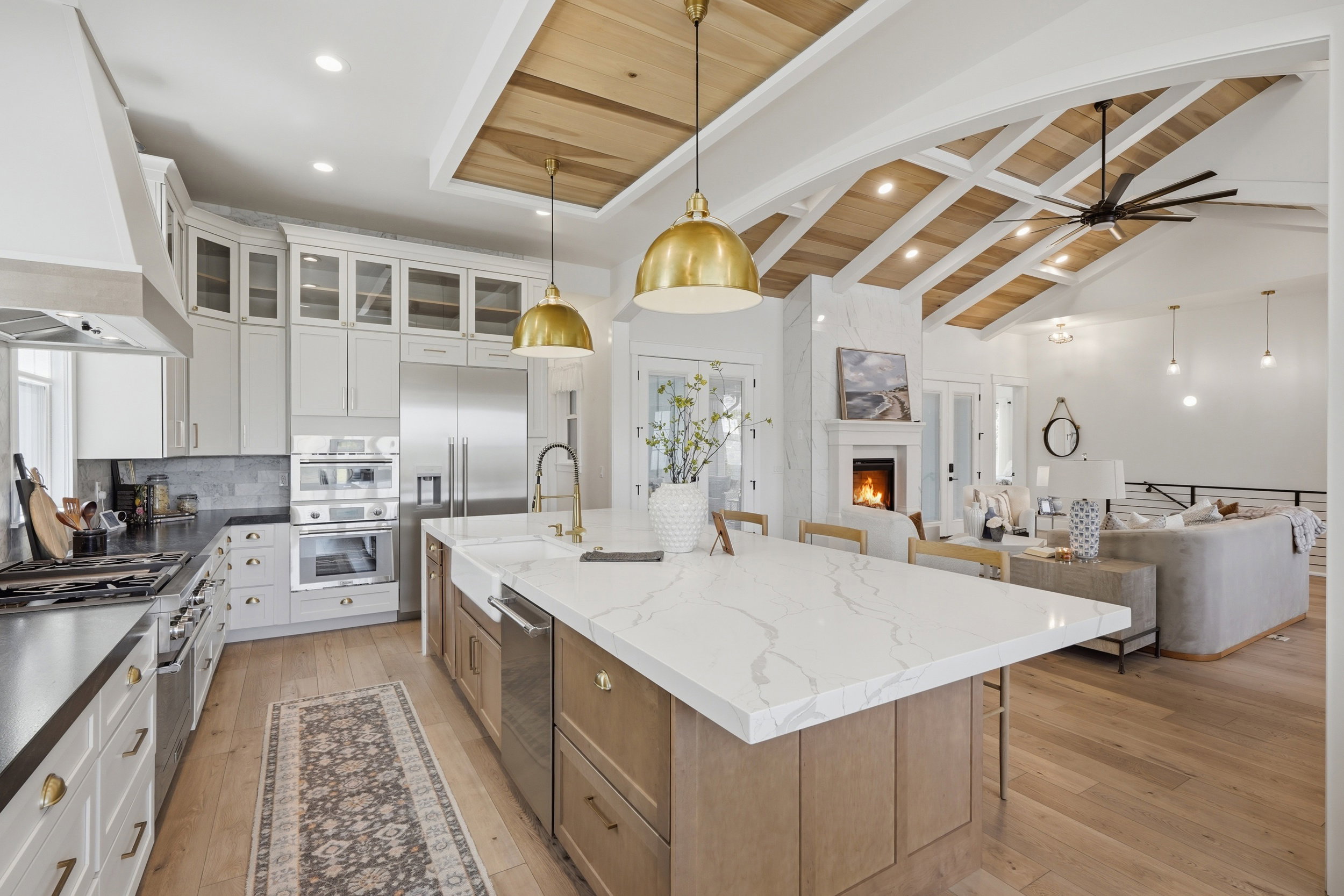 Gourmet kitchen with a large central island, white shaker cabinetry, stainless steel appliances, and wood-finish flooring