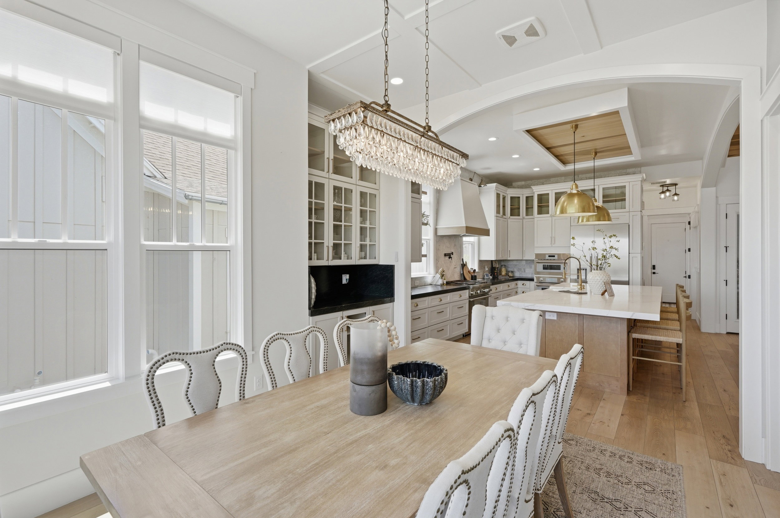 Open-concept dining area featuring a crystal chandelier, wood-finish flooring, and arched entryway