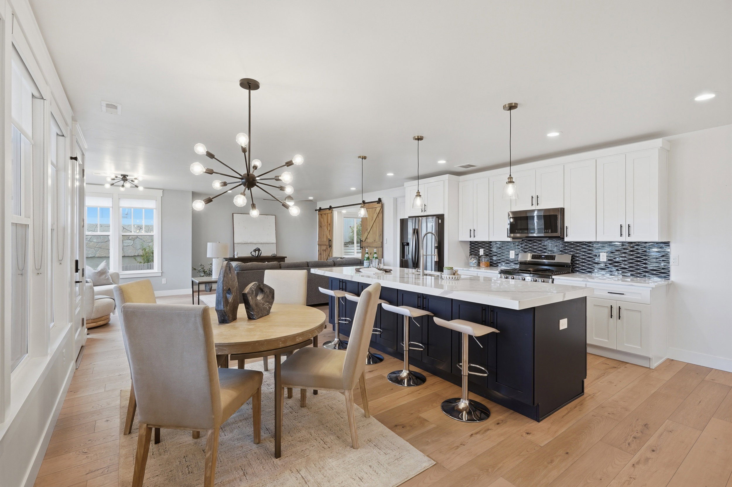 Open-concept living space featuring wood-finish flooring, a contemporary dining chandelier, and recessed lighting