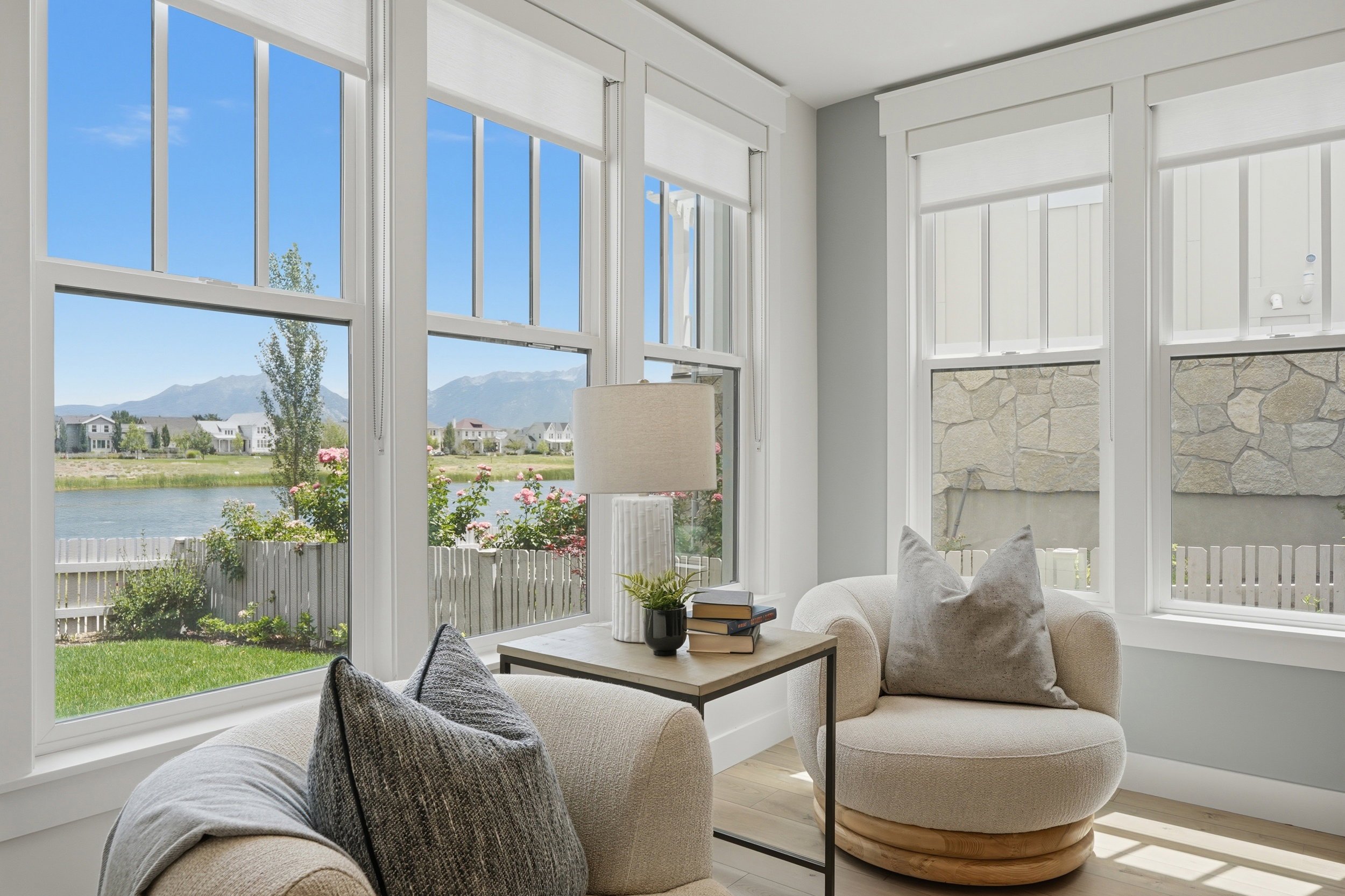 Bright living space featuring multiple large windows with white trim, offering views of a body of water and distant mountains