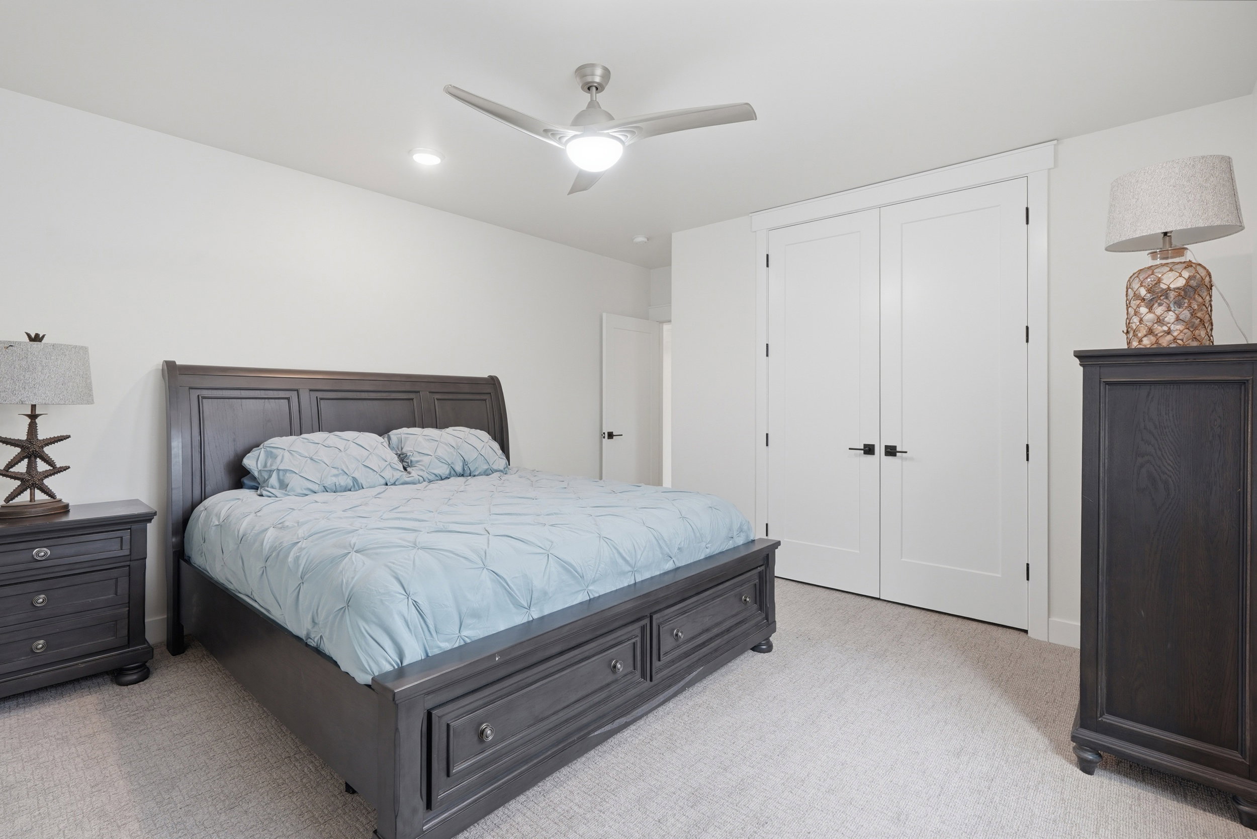Neutral-toned carpeting extends throughout this room, featuring a contemporary ceiling fan with integrated lighting