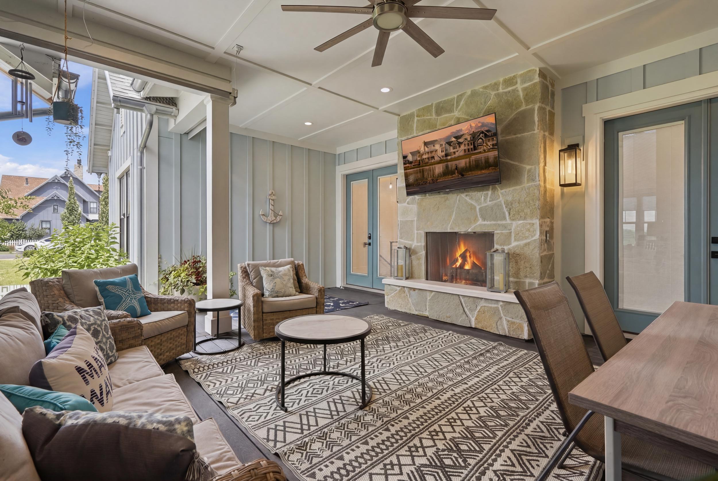 Covered outdoor living area featuring a stone-clad fireplace and light-colored wood-finish flooring