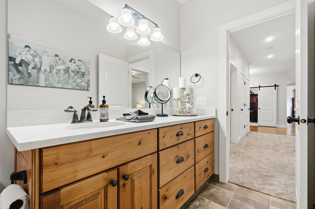 Bathroom vanity featuring a light wood-finish double cabinet, a white stone-finish countertop with an integrated sink, and an overhead vanity light fixture