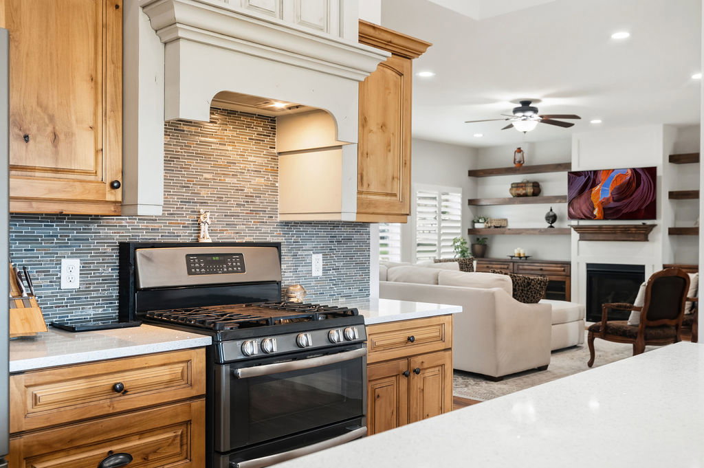 Stainless steel range with a mosaic tile backsplash and custom wood-finish cabinetry
