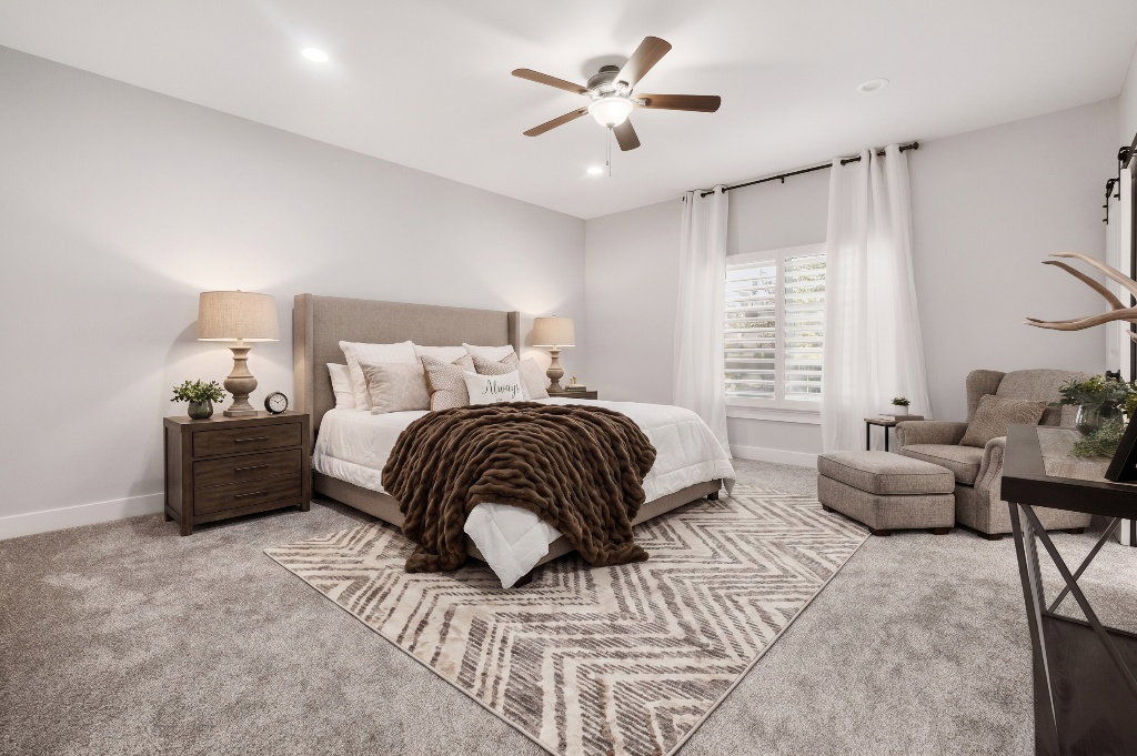 Spacious bedroom featuring light gray carpeting and a ceiling fan