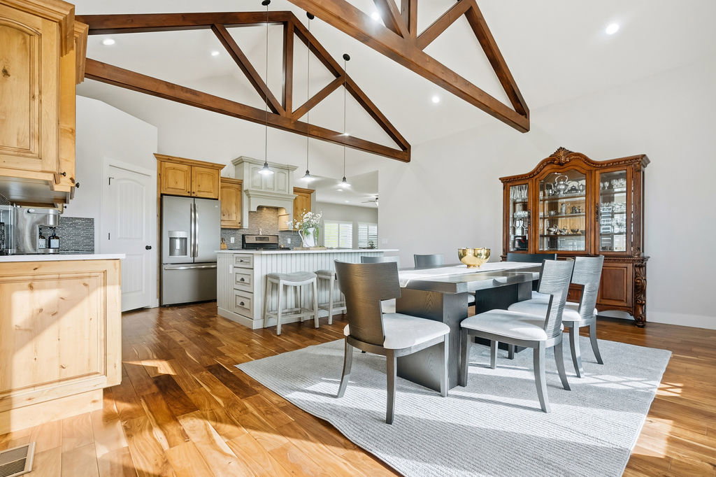 Vaulted ceilings with exposed timber beams define this expansive space, featuring wood-finish flooring throughout