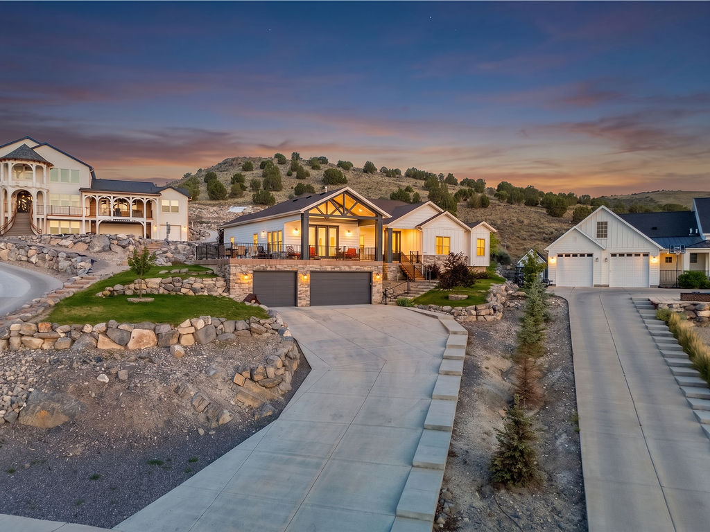 Hillside residence featuring a white facade with stone accents and a prominent two-car garage