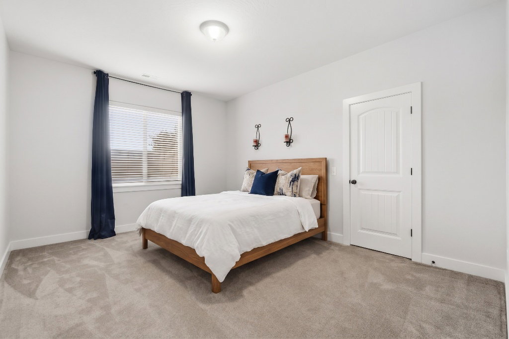 Spacious room featuring neutral carpeting, a large window with blinds, and white trim throughout