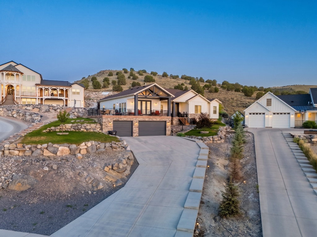 Modern farmhouse-style residence featuring a two-car garage with stone detailing, a covered balcony, and a prominent gable roofline
