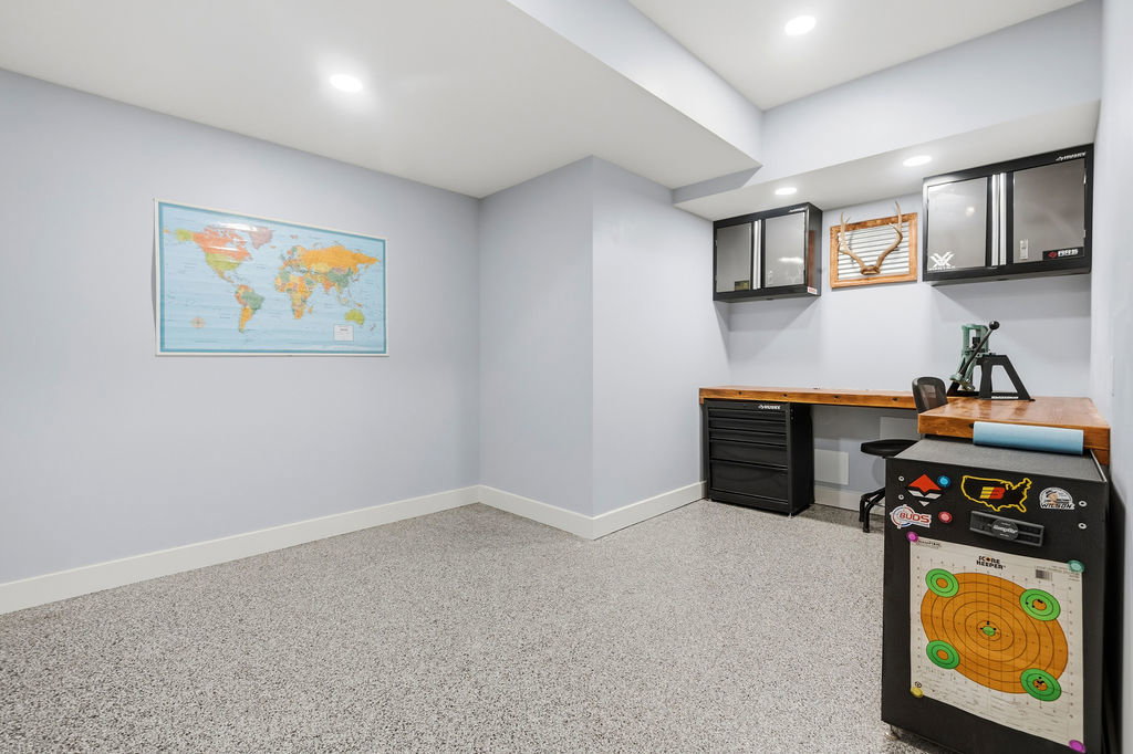 Lower-level room with light gray walls, white baseboards, and durable speckled flooring