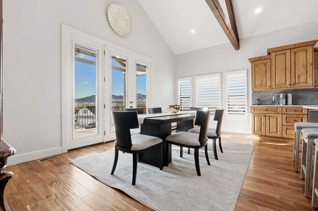 Dining area with vaulted ceilings, exposed wood beams, and hardwood flooring