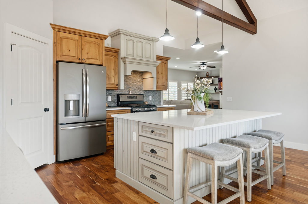 Kitchen featuring a substantial island with beadboard paneling and a light-toned countertop, stainless steel appliances, and wood-finish flooring